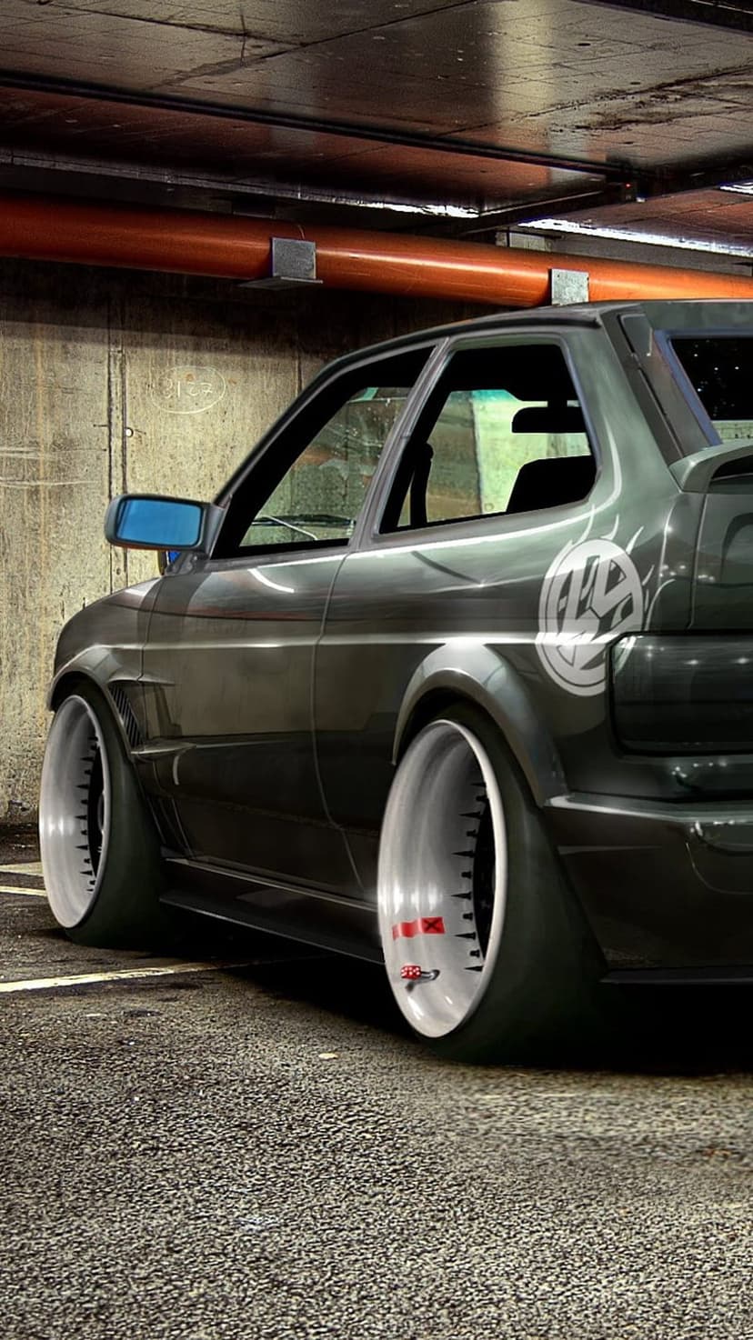 VW Golf Mk2 with flared widebody fenders and deep dish wheels parked inside a dark, atmospheric industrial garage.