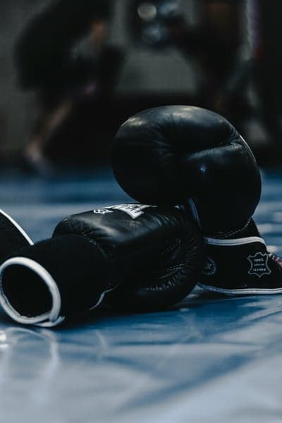 Black Boxing Gloves on a Blue Mat