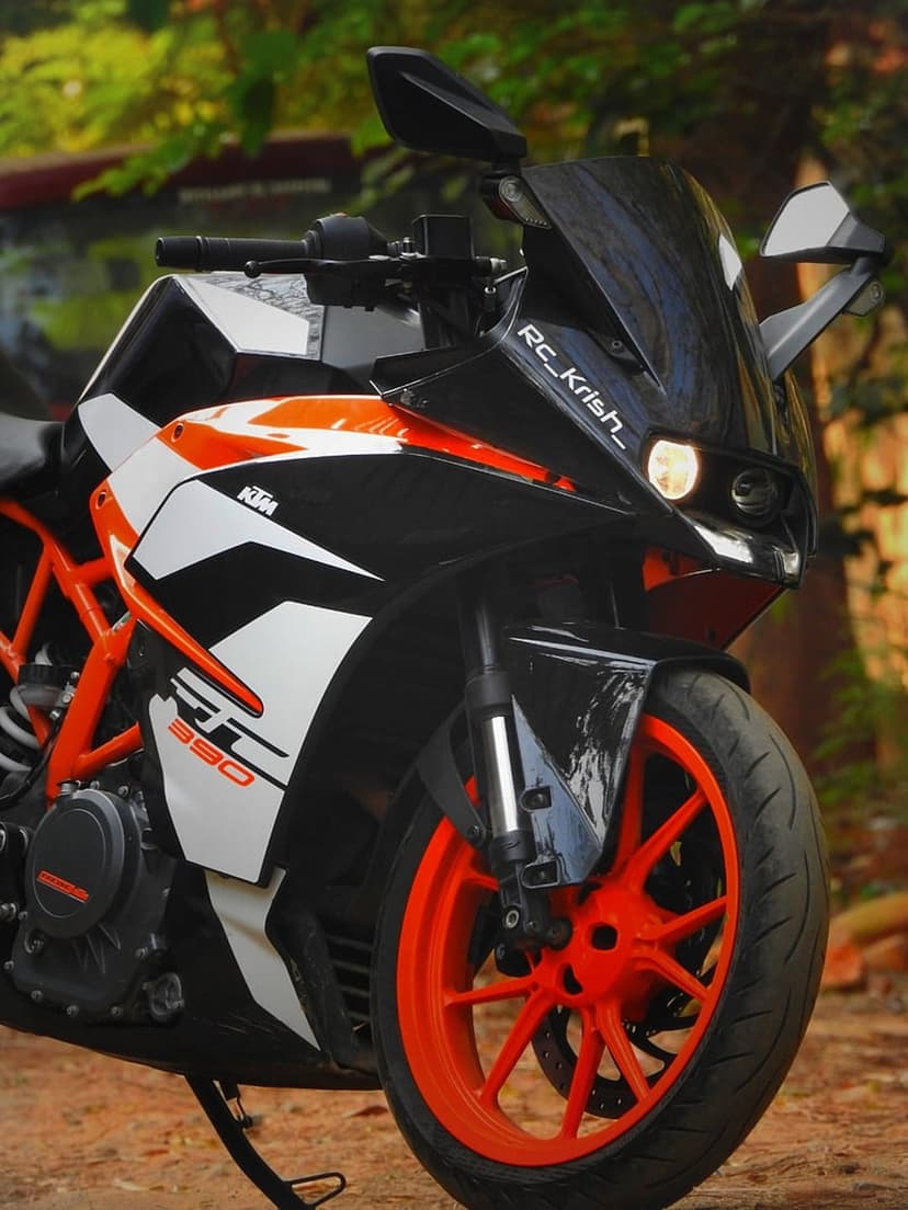 KTM RC 390 motorcycle displays sharp front fairing lines and orange wheels in a close-up portrait view.