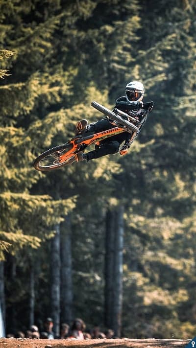 Mountain biker soars through air over forest background