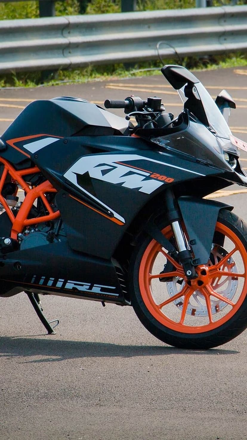 KTM RC 200 motorcycle with orange wheels and trellis frame parked on an asphalt road under natural light.