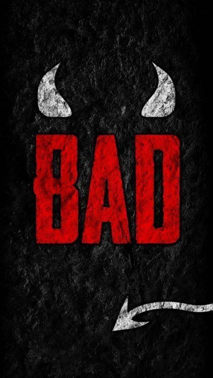 Red BAD lettering with white devil horns and tail rests on a dark, textured charcoal background surface.