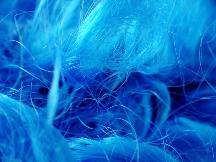 Interlocking vibrant blue fibers and microscopic threads overlap with soft bokeh and sharp textural highlights.