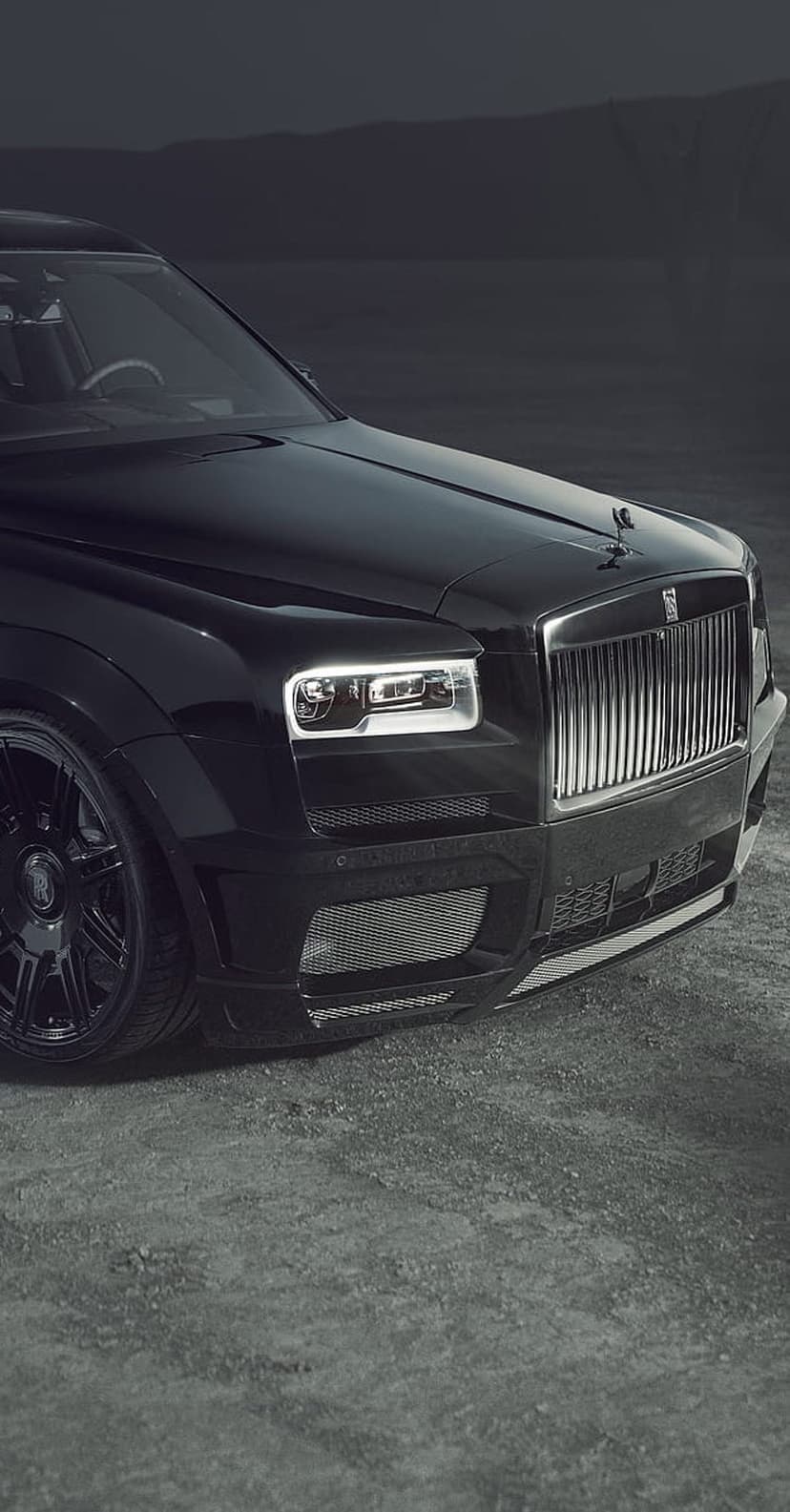 Rolls-Royce Cullinan front grille glowing at night with detailed LED headlights on a black luxury SUV body.