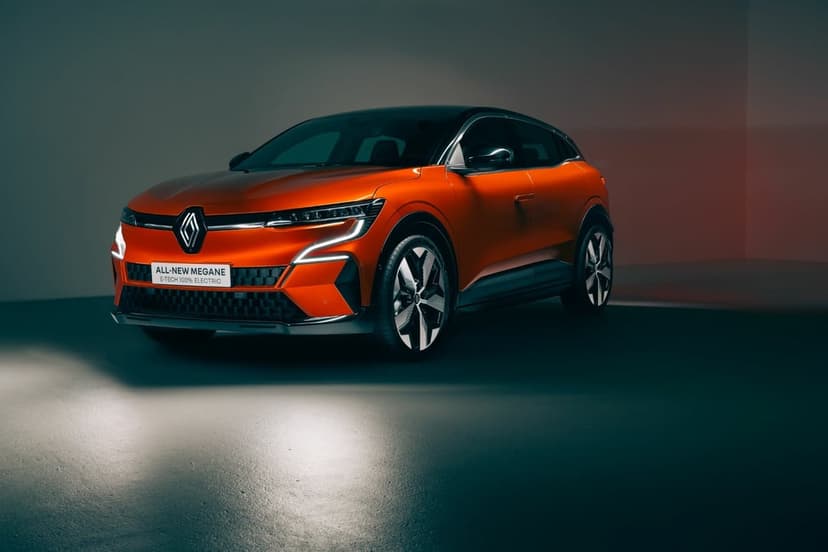 Metallic orange electric car with sharp LED lights on a dark reflective floor with dramatic studio lighting.