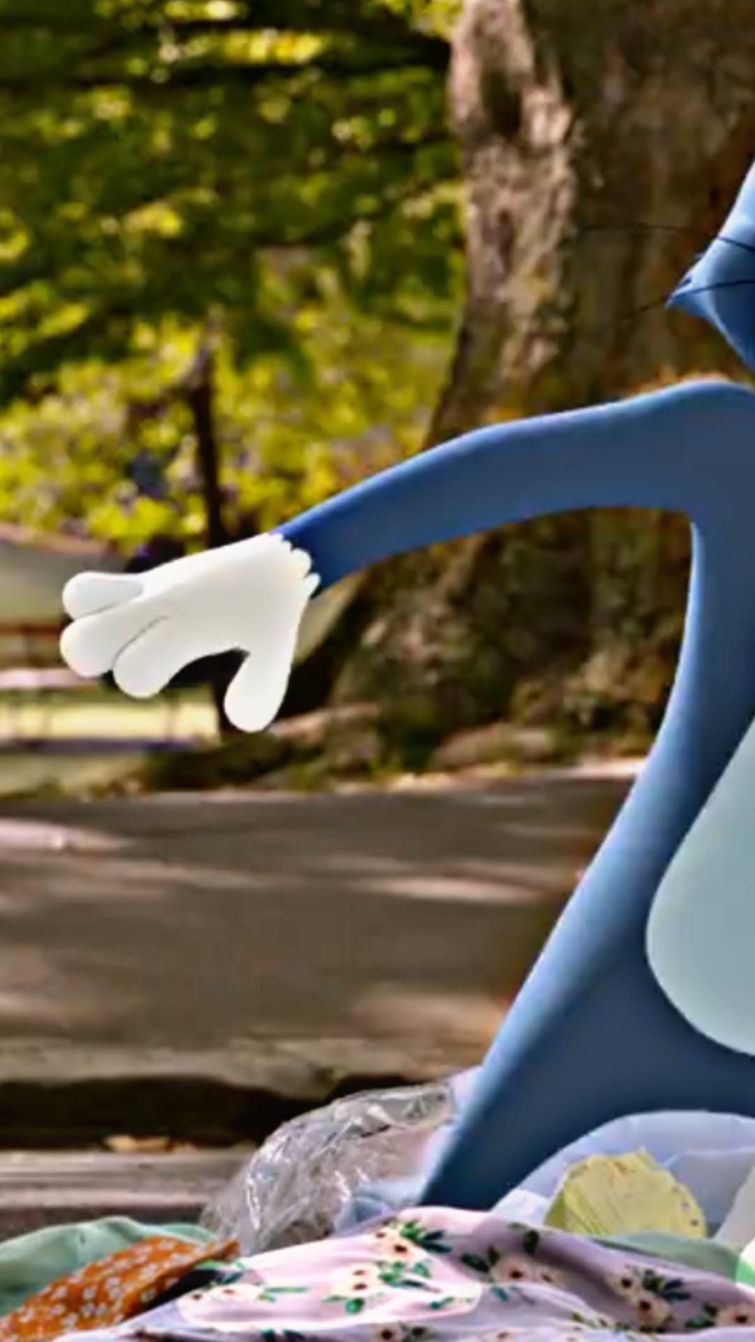 Sonic the Hedgehog's white-gloved hand reaches for discarded plastic and clothing on a park pathway.