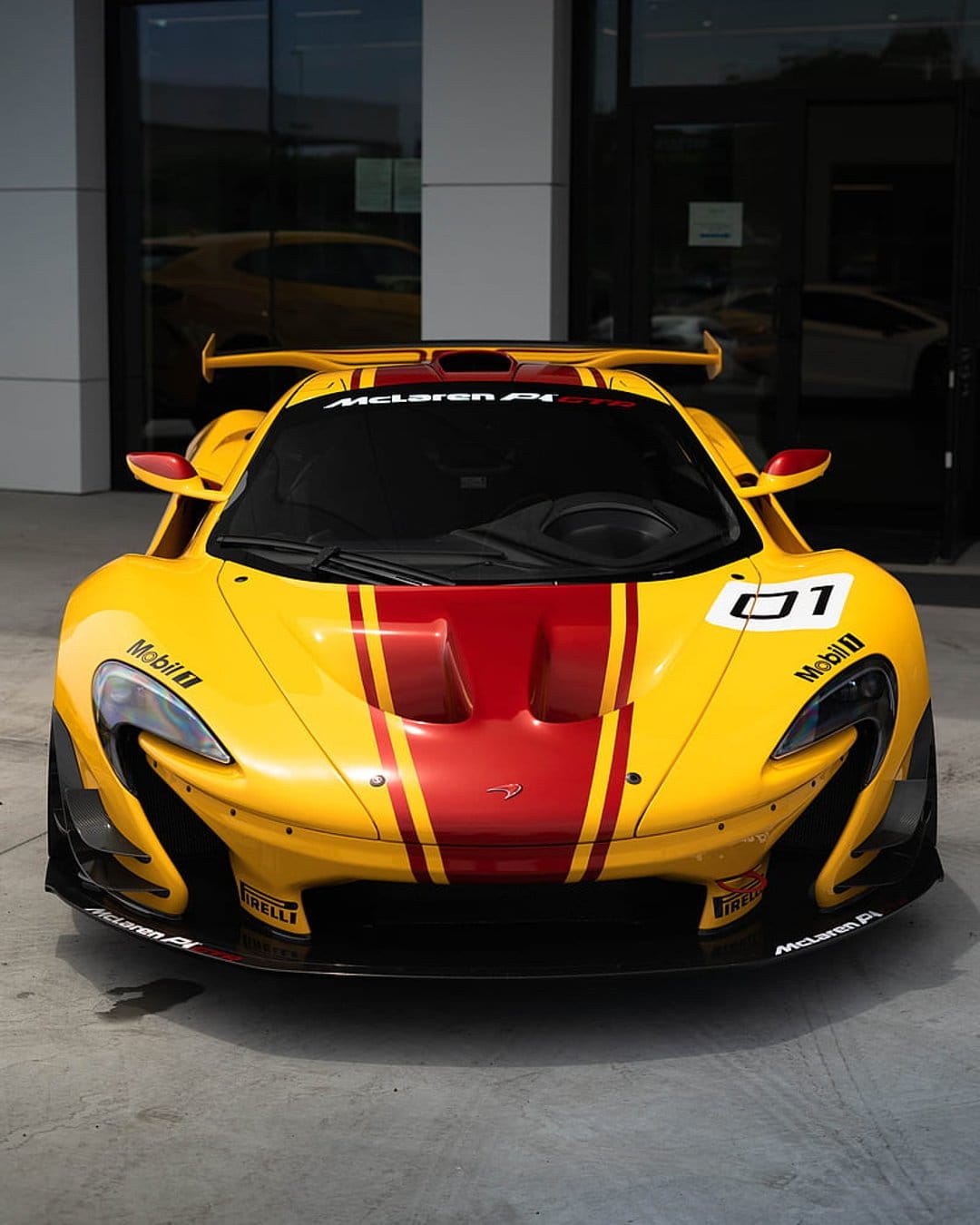 Yellow McLaren P1 GTR track car with red stripes, carbon fiber aerodynamics, and racing decals on a white ground.