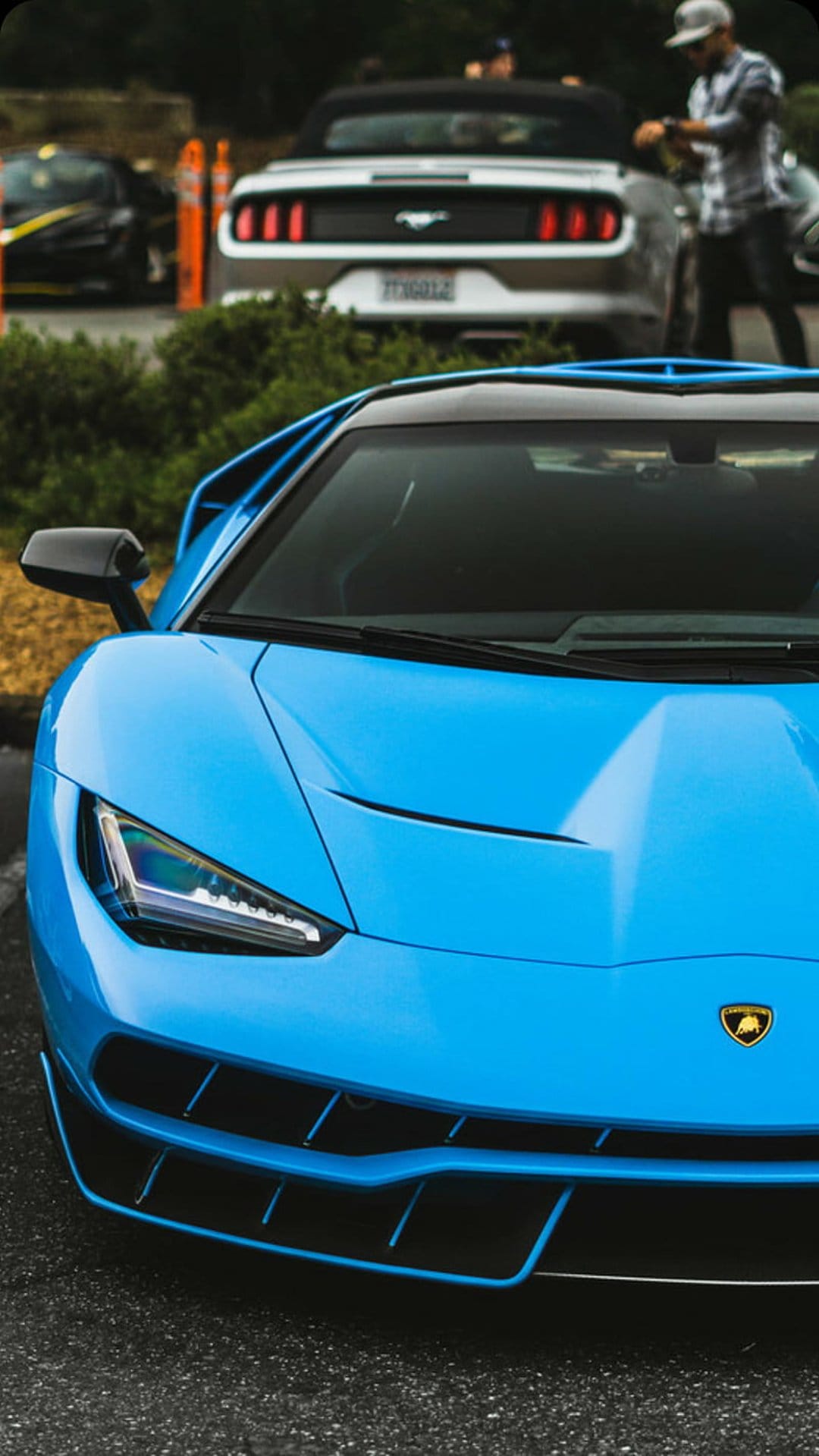 Blue Lamborghini Centenario shows sharp front aerodynamic lines and glowing headlights on a sleek blue body.