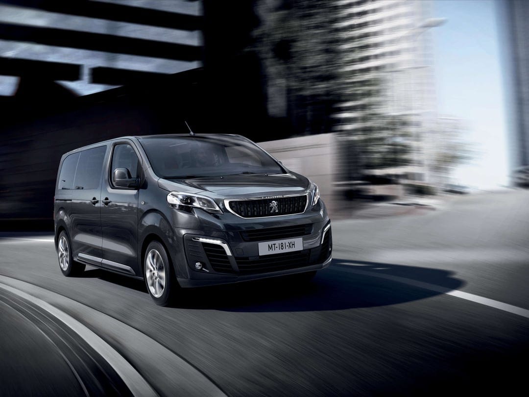 Dark grey Peugeot van driving on a curved city road with motion blur backgrounds and metallic details.