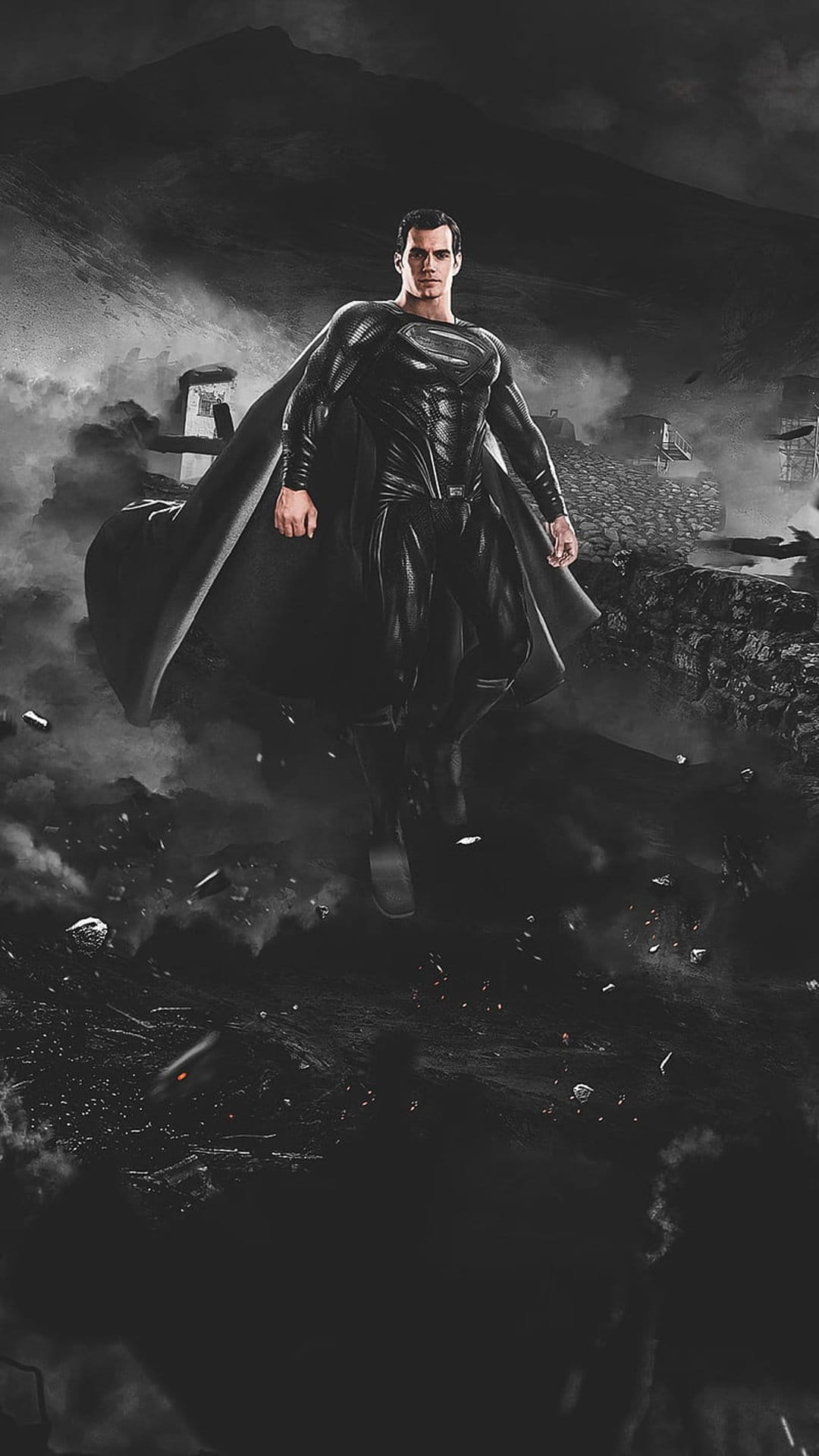 Superman in a black suit flies above smoking ruins and jagged mountains under a dark, overcast sky.
