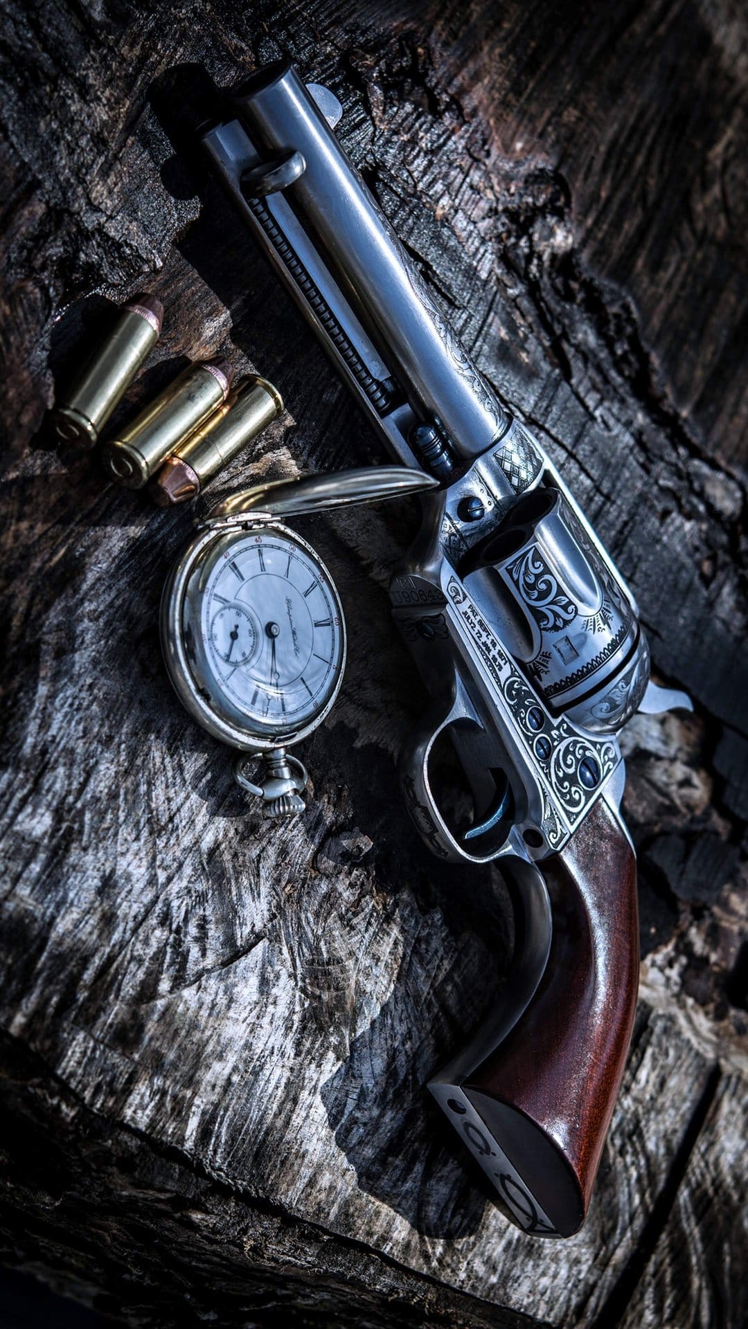 Engraved silver revolver, golden pocket watch, and three bullets resting on a dark, textured wood surface.