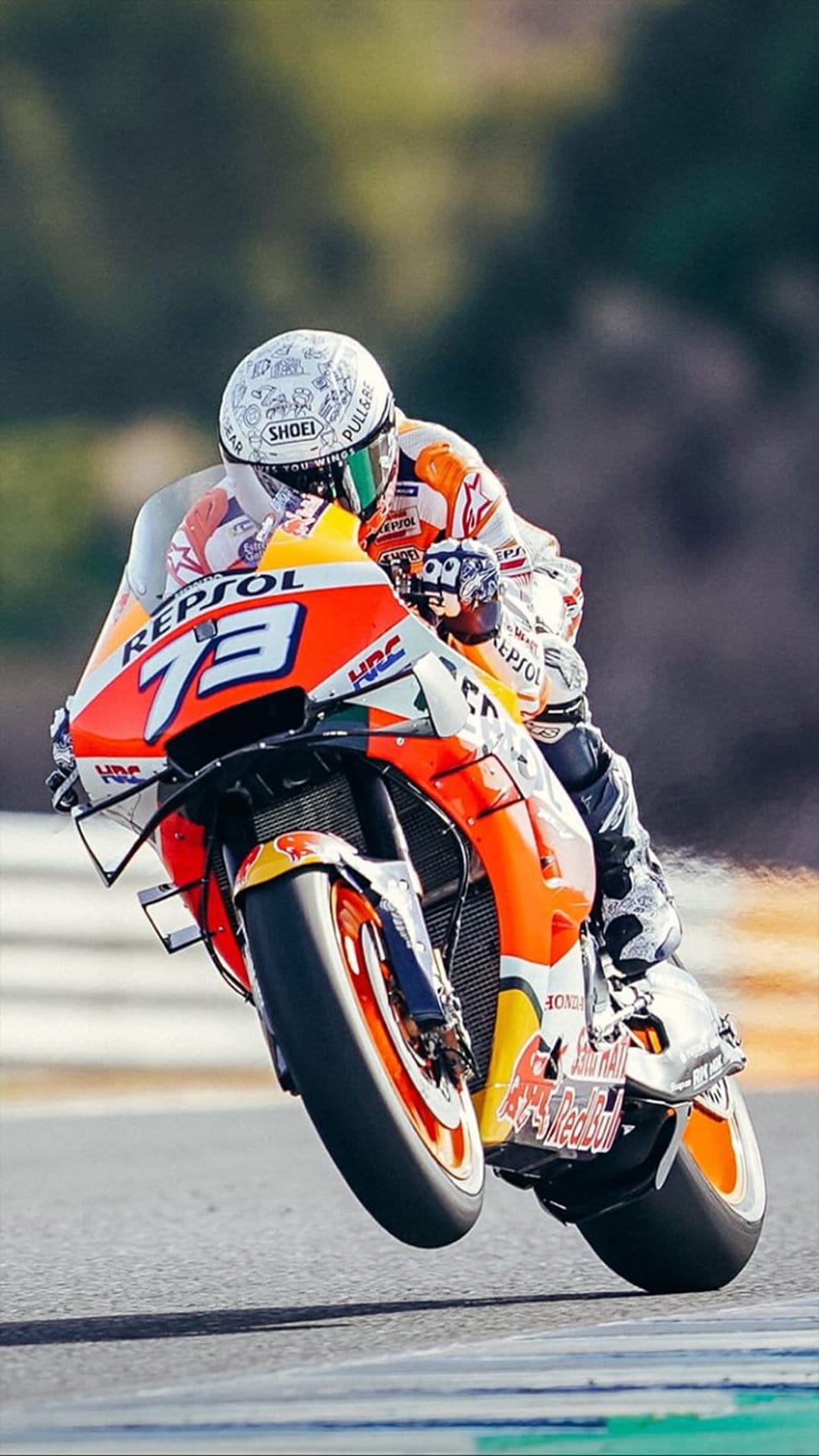 Motorcycle racer in an orange Repsol Honda suit leans low into a track turn with a white helmet and racing bike.