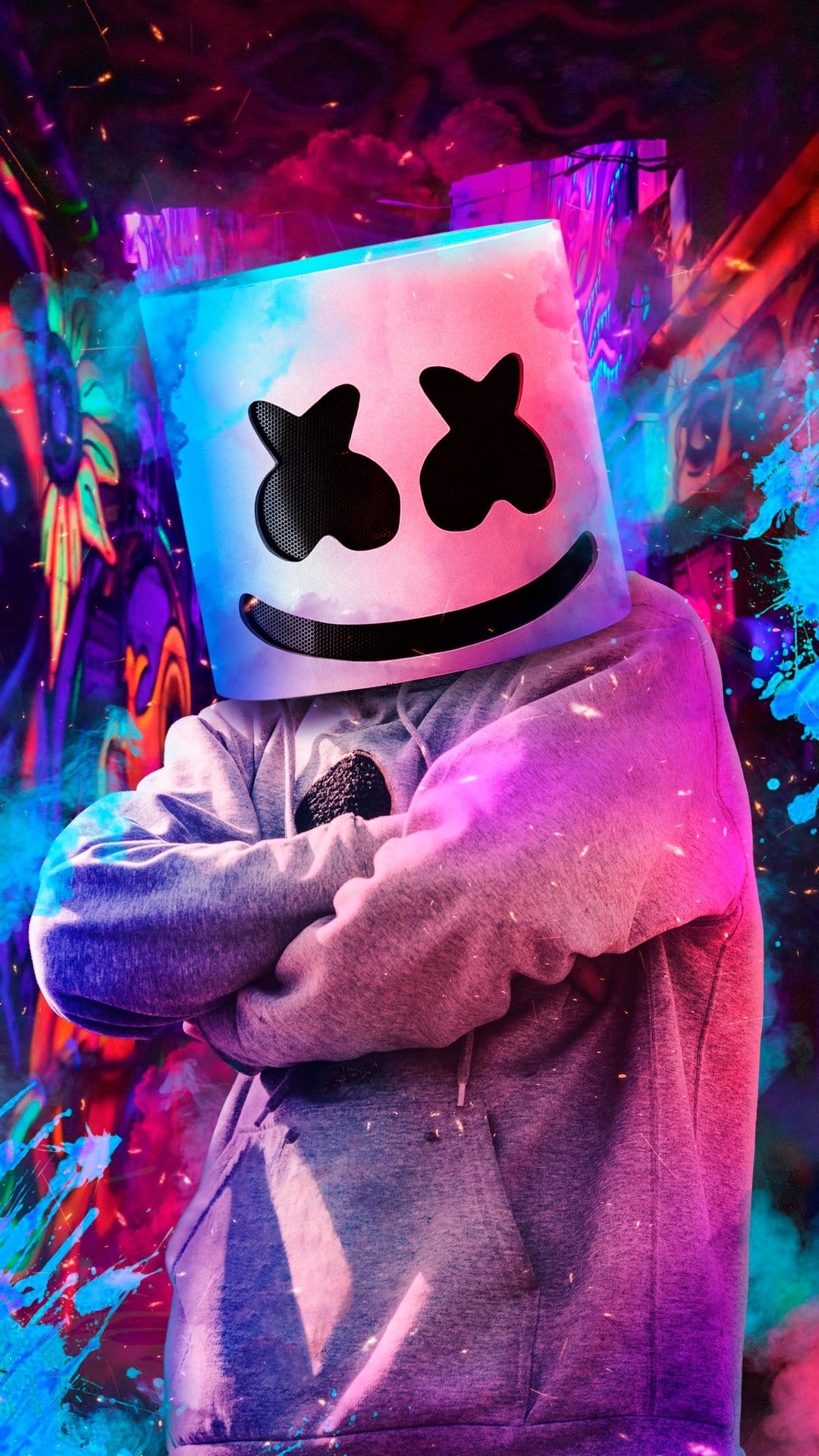 Marshmello wearing his white helmet glows under neon pink and blue lighting with abstract colorful smoke clouds.