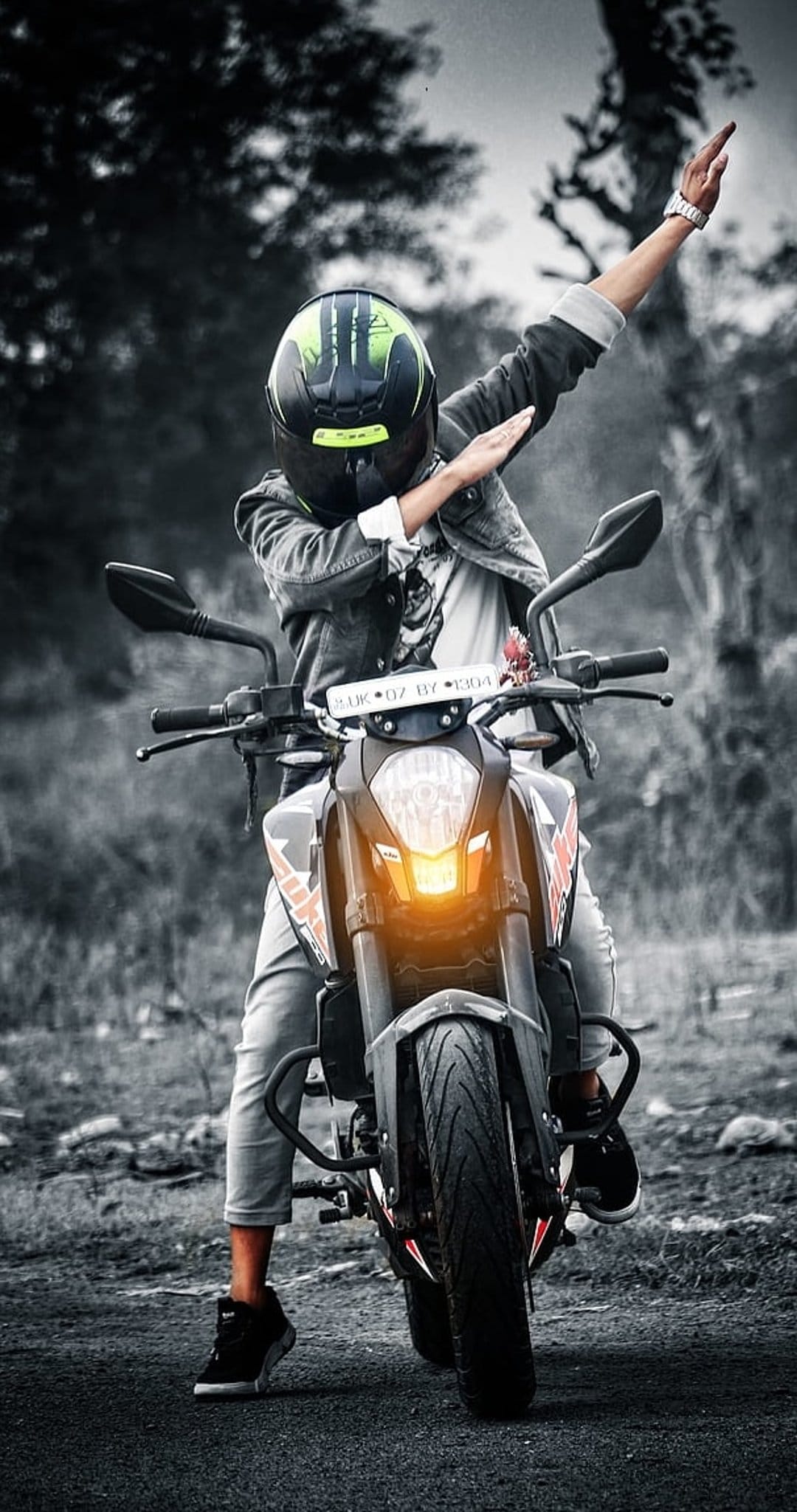 Motorcyclist in a denim jacket poses with arms out on a bike featuring a glowing orange headlight.
