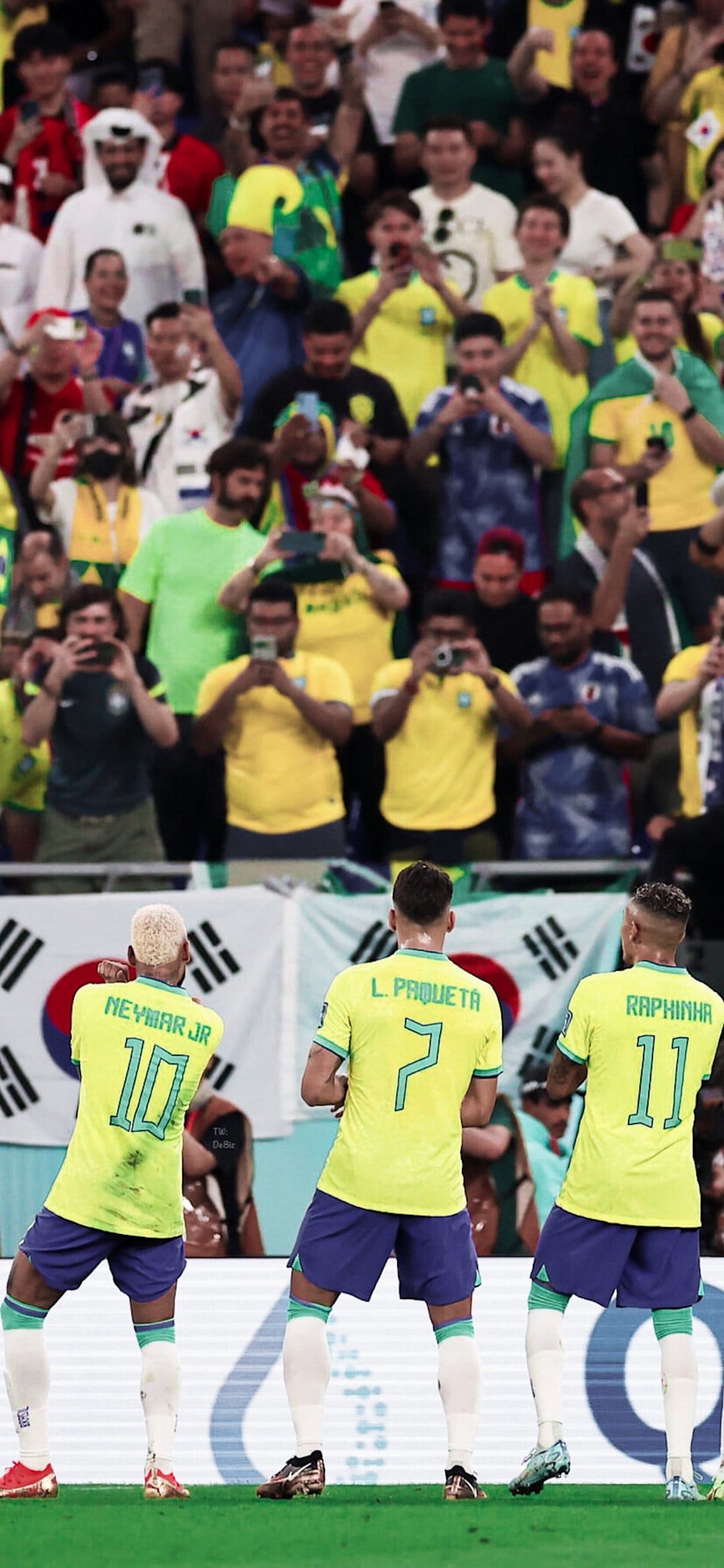 Neymar Jr, Paqueta, and Raphinha celebrate a goal in yellow Brazil kits amidst a cheering stadium crowd.
