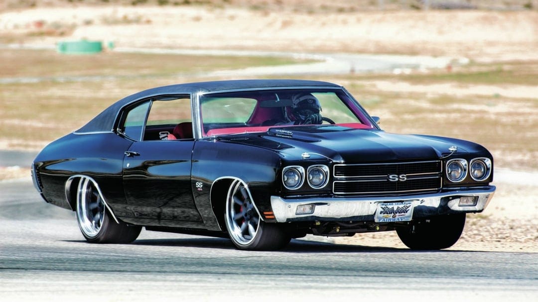 Black Chevrolet Chevelle SS racing on an asphalt track with a bright red interior and chrome details.