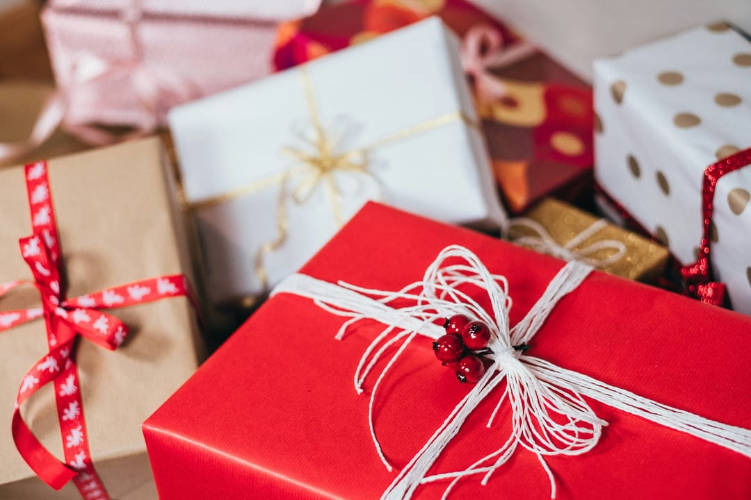 Christmas gift boxes wrapped in red and white paper with silk ribbons and kraft paper textures in a close-up.