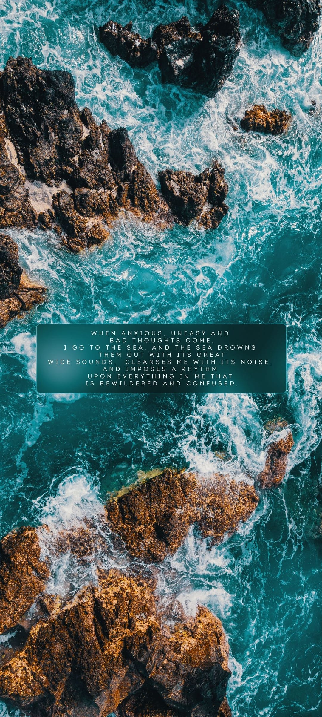 Turquoise ocean waves collide with dark coastal rocks beneath a central translucent box containing a white quote.