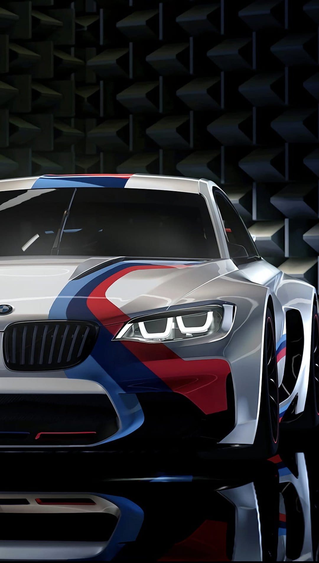 BMW M performance car front with silver paint, tricolor racing stripes, and sharp headlights on a dark background.