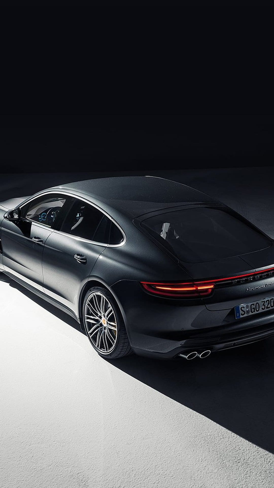 Porsche Panamera rear three-quarter view with glowing red LED taillights and dual exhausts in a dark studio.
