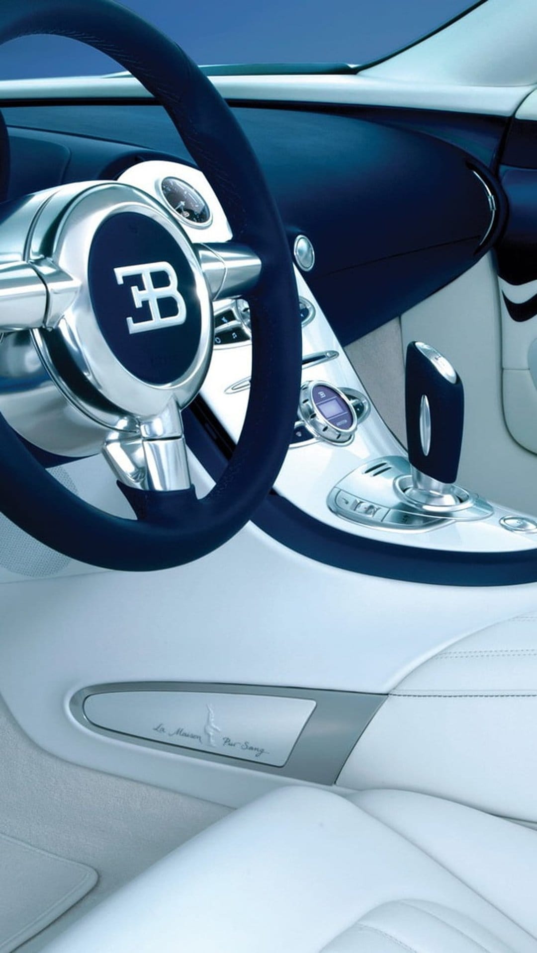 Bugatti Veyron steering wheel with EB logo and white leather gear shift in a luxury supercar cockpit.