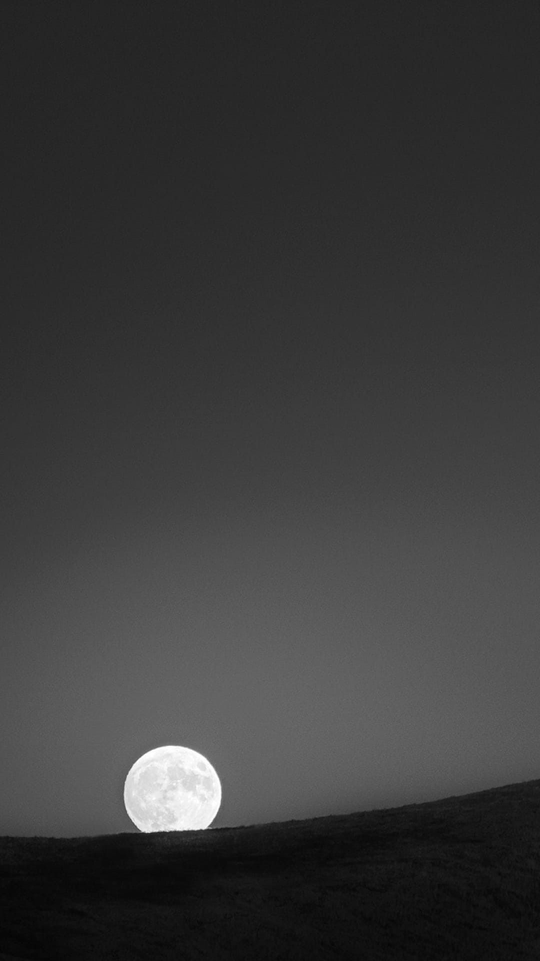 Full moon glowing brightly above dark silhouetted hills in a minimalist black and white nocturnal landscape.