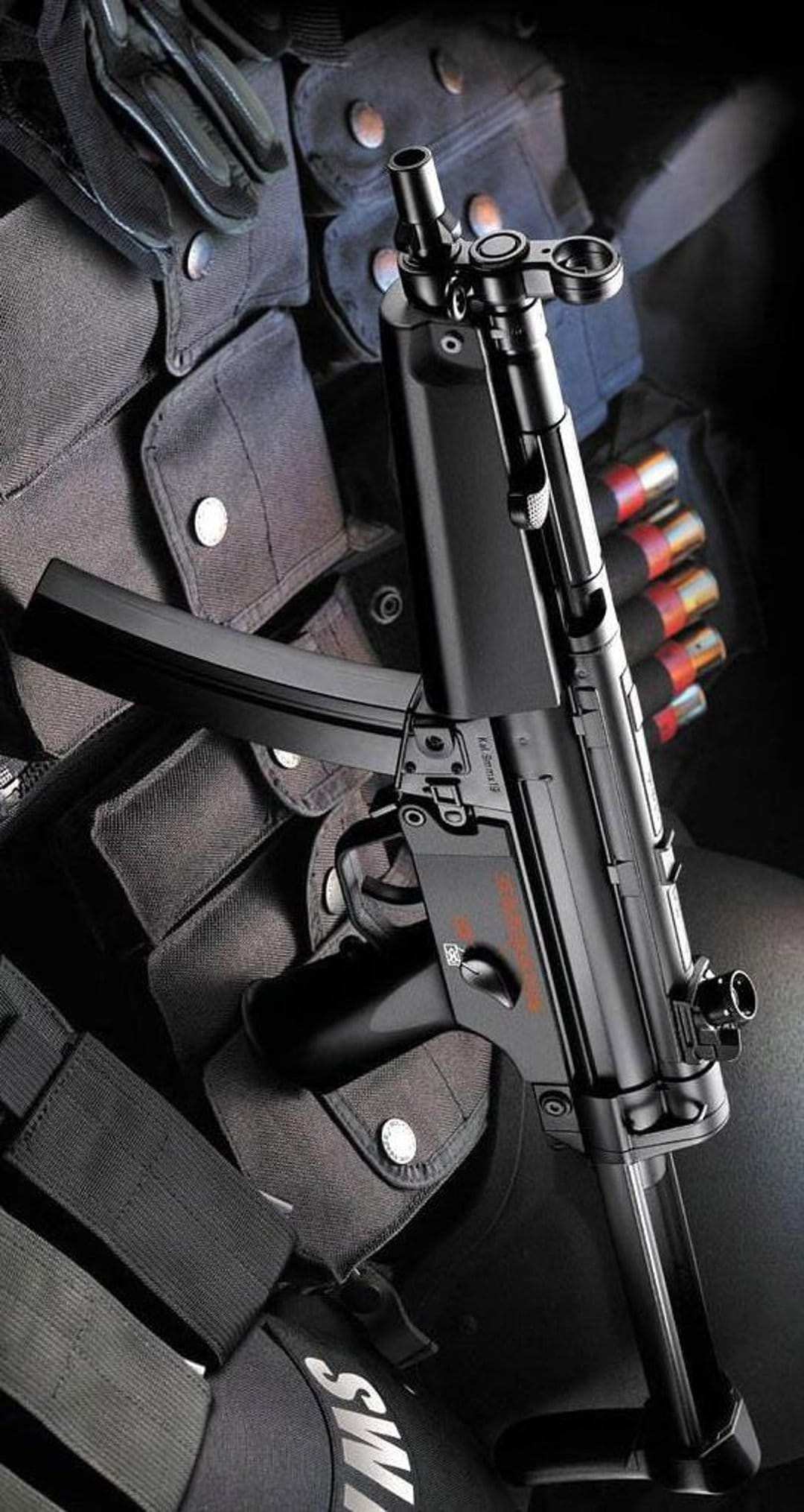 MP5 submachine gun with a loaded magazine positioned on black SWAT tactical gear including pouches and holsters.