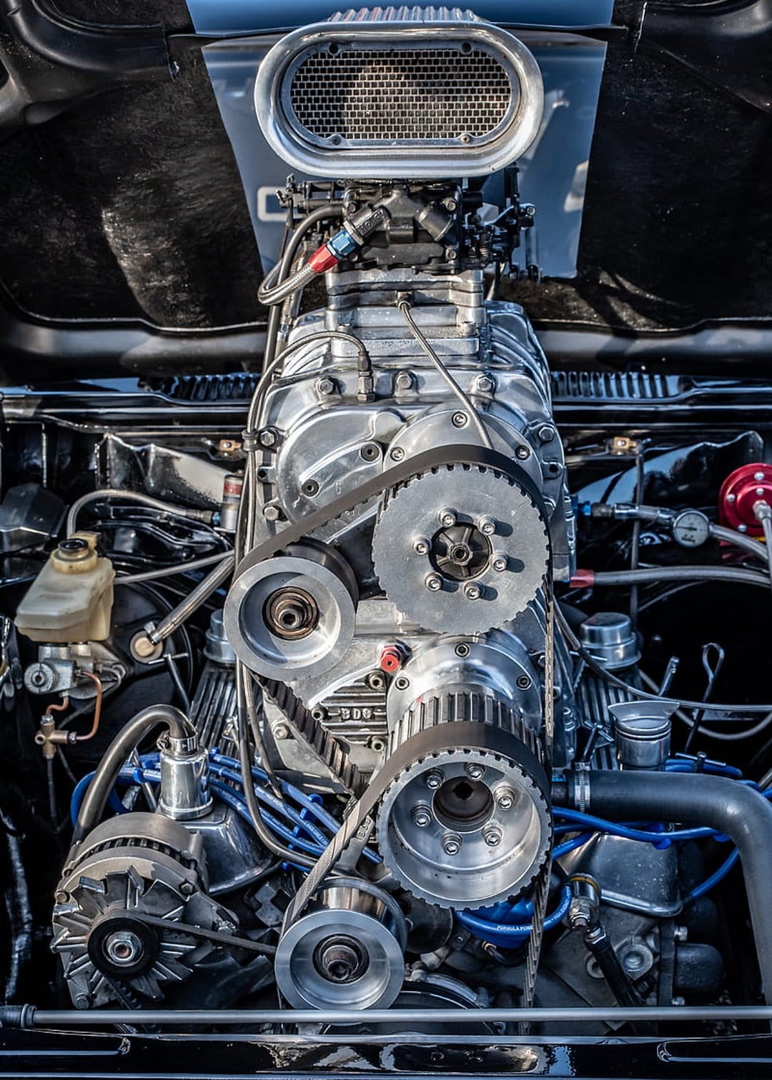 Supercharged V8 engine features polished chrome pulleys and a black intake blower for a high-performance look.