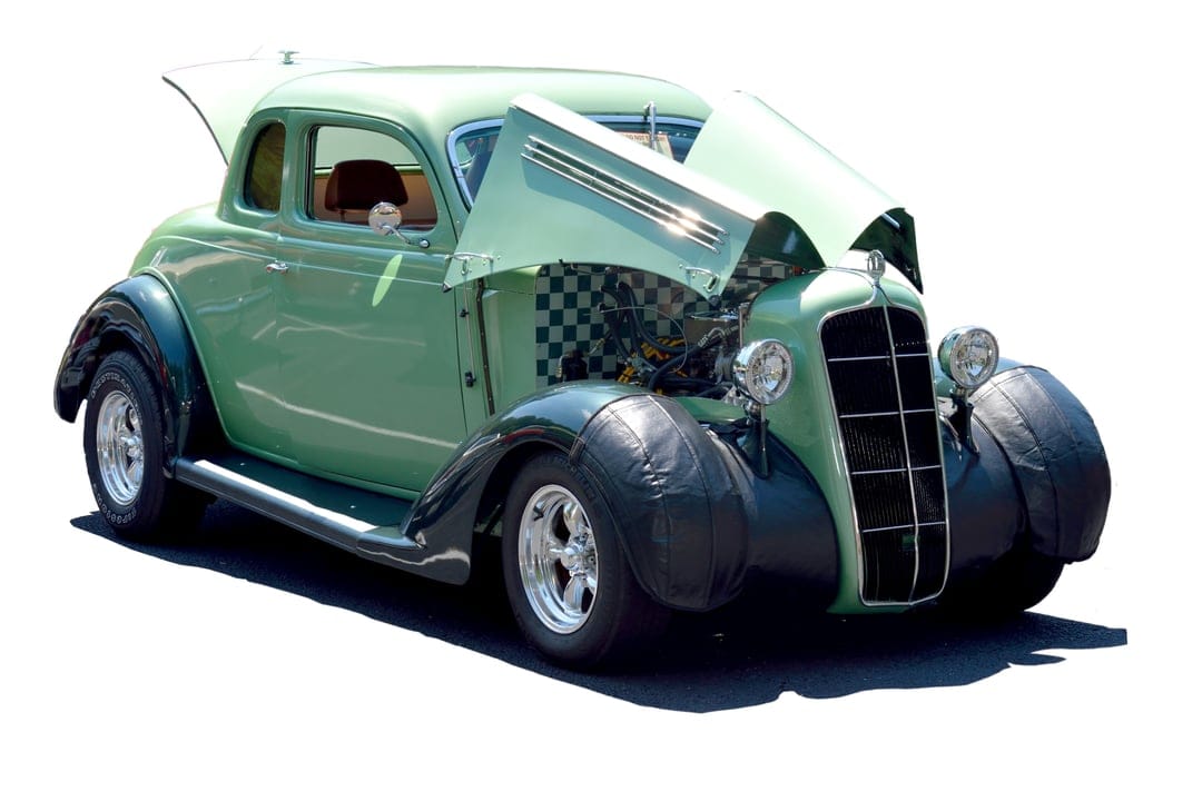 Mint green vintage hot rod coupe with an open hood, checkered firewall, and chrome wheels on a white background.