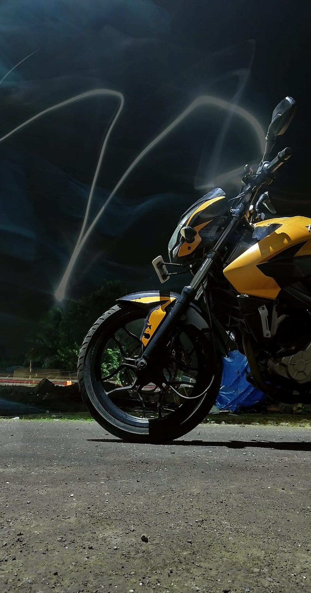 Yellow sportbike motorcycle with black accents surrounded by swirling white and yellow light trails at night.