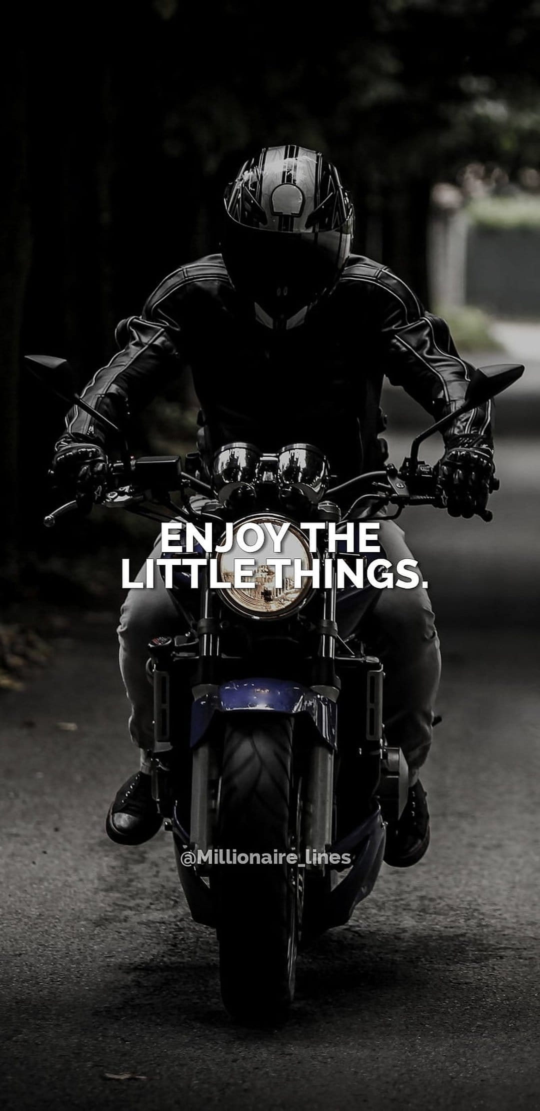 Motorcyclist in full riding gear leans on a road alongside the quote Enjoy the little things in black and white.