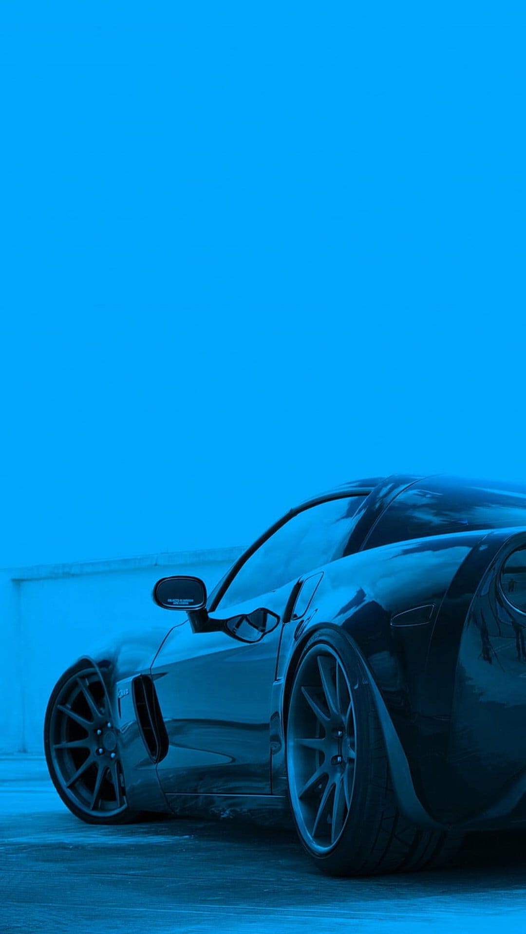 Black sports car with custom rims against a solid blue background, shown from a low-angle aggressive perspective.