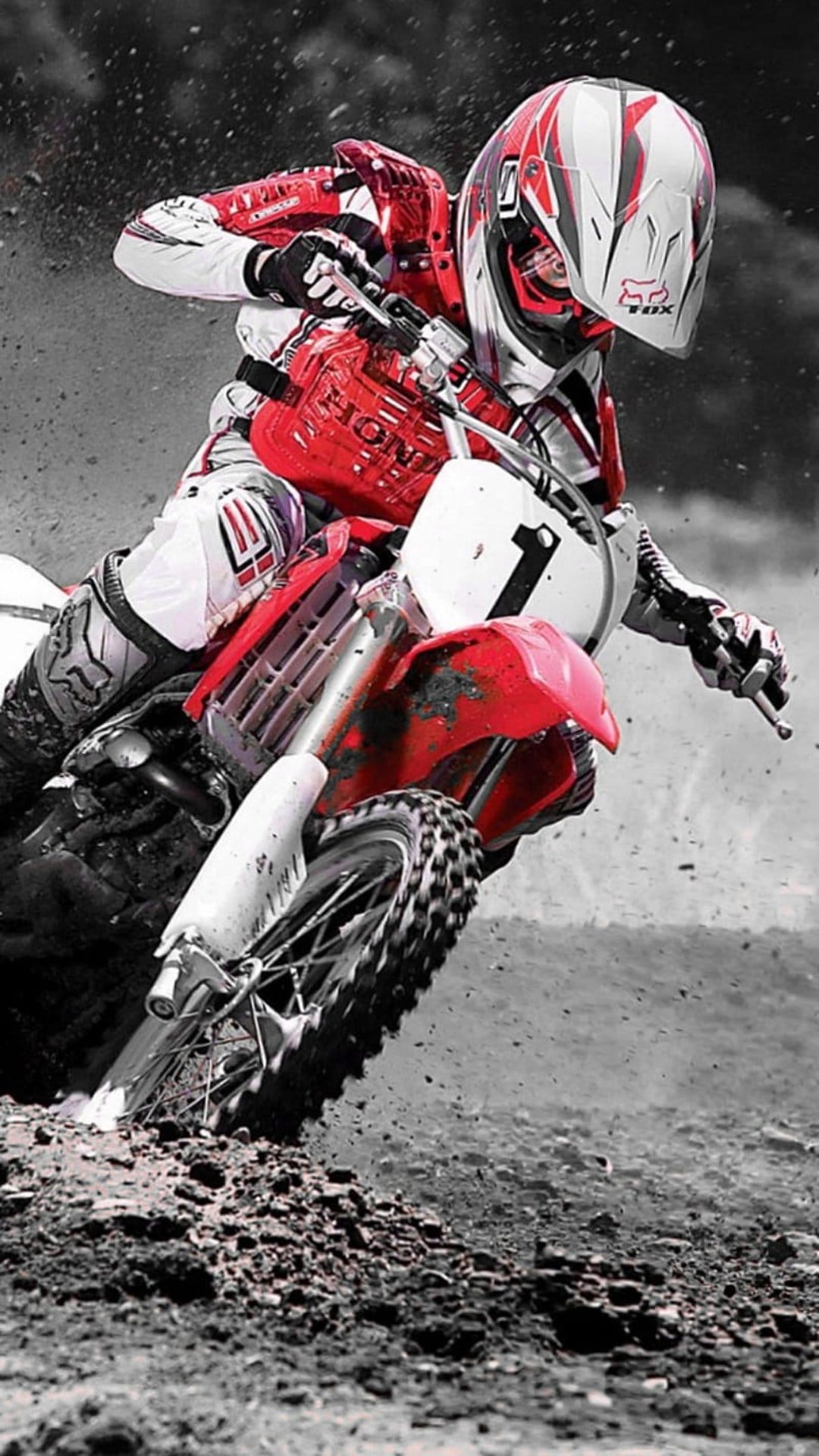 Motocross athlete in red gear maneuvers a Honda bike through a turn, kicking up a large spray of brown dirt.