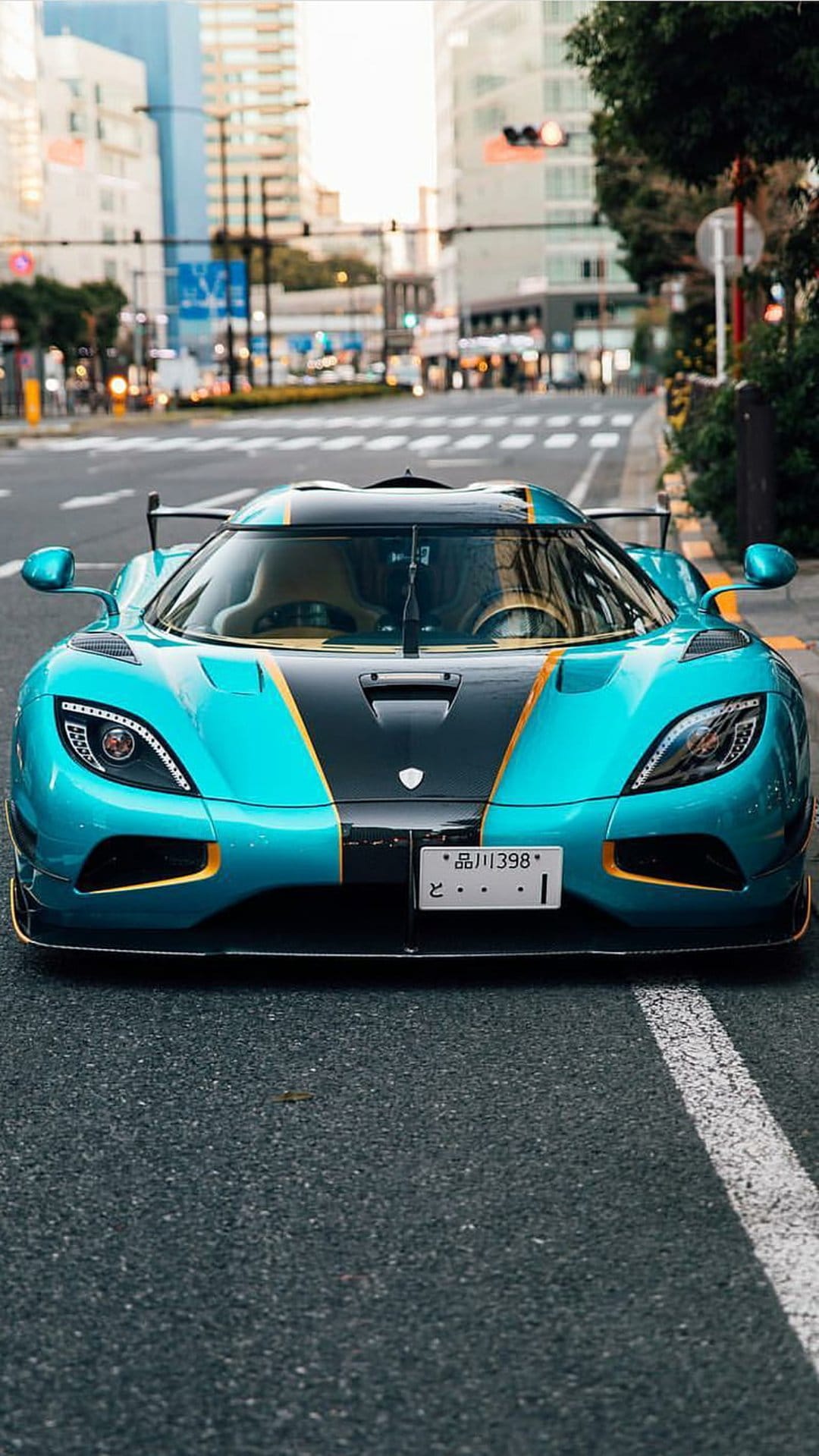 Koenigsegg Agera RS in bright blue with gold accents parked on a city street during the day from a low perspective.