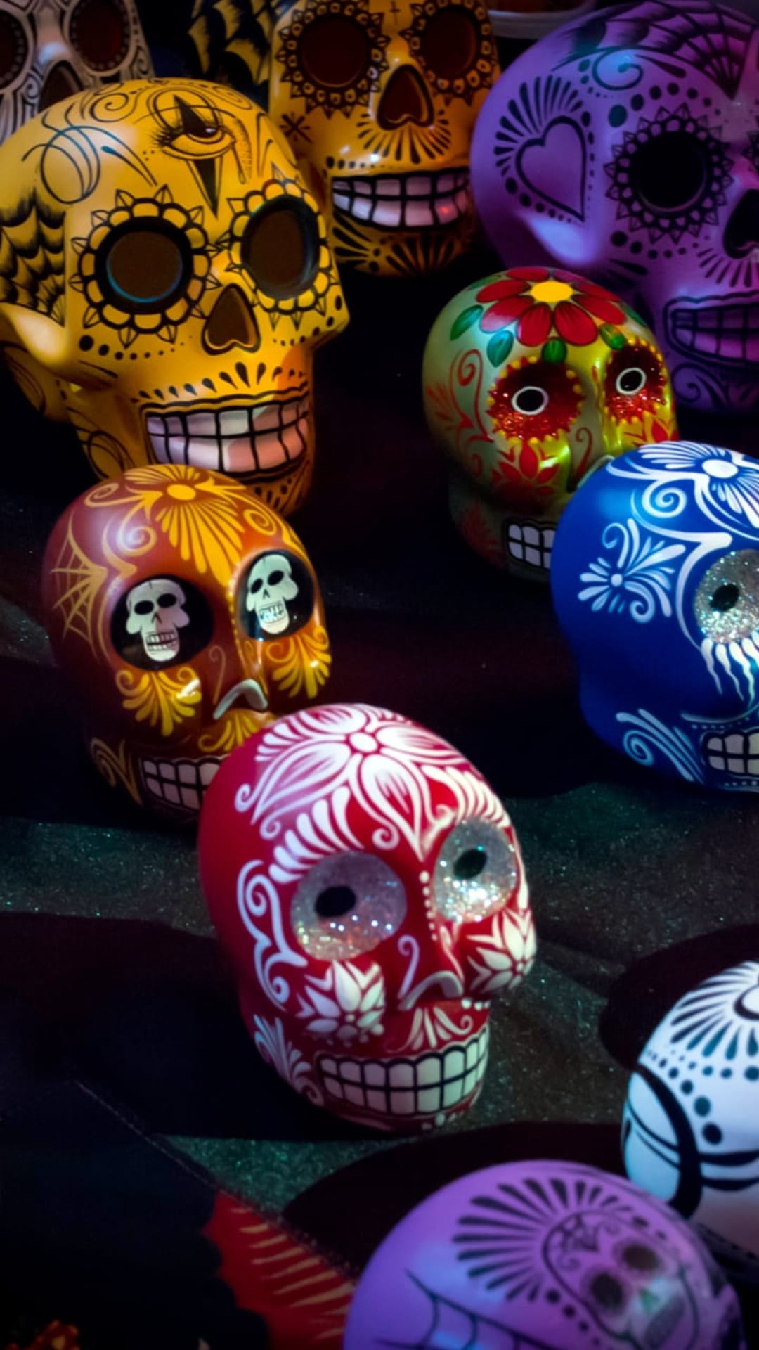 Intricately decorated sugar skulls featuring floral motifs and swirling patterns in bright red, yellow, and blue.