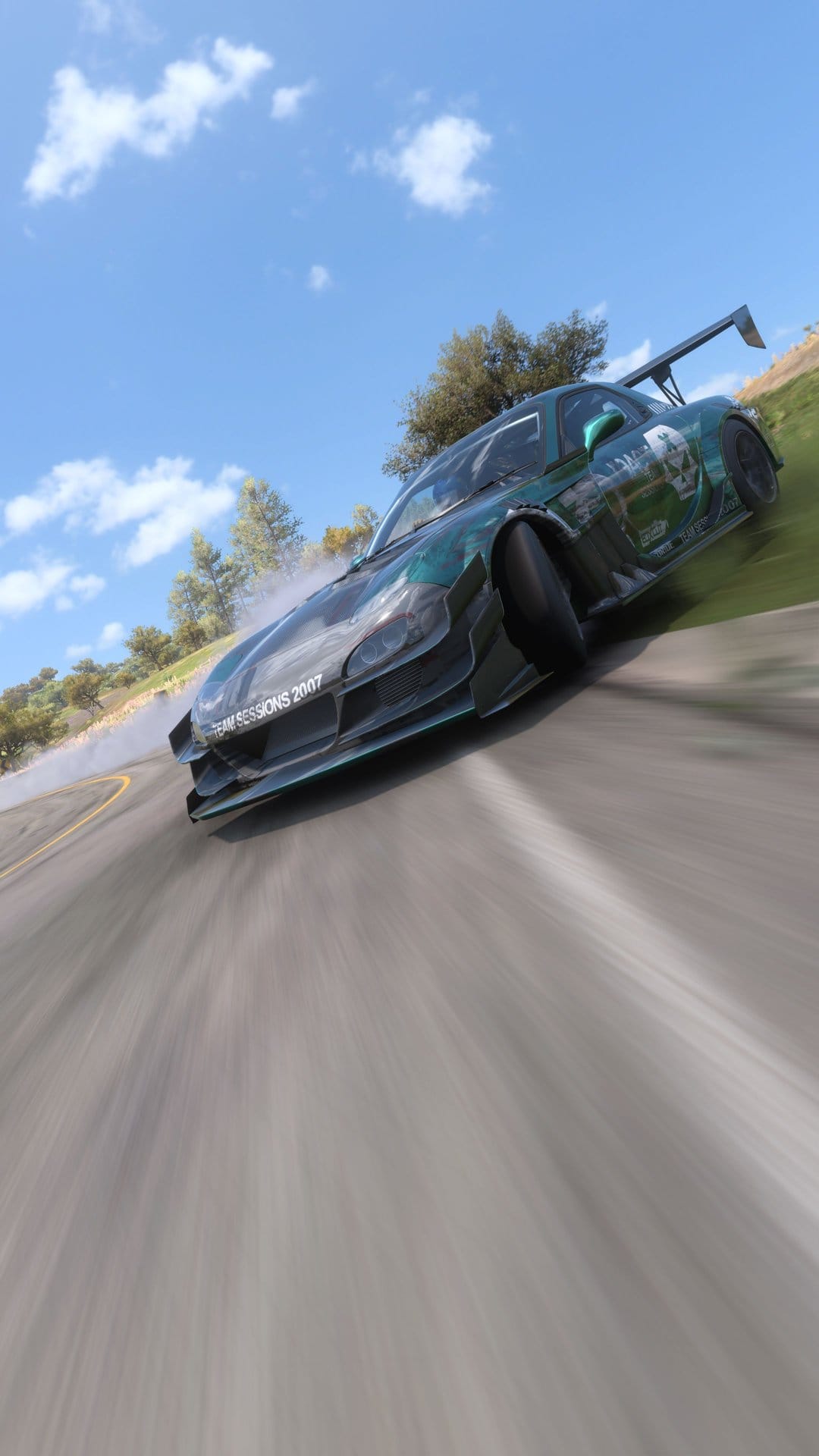 Green sports car drifting around a paved corner with white tire smoke against a sunny hill and cloudy sky background.
