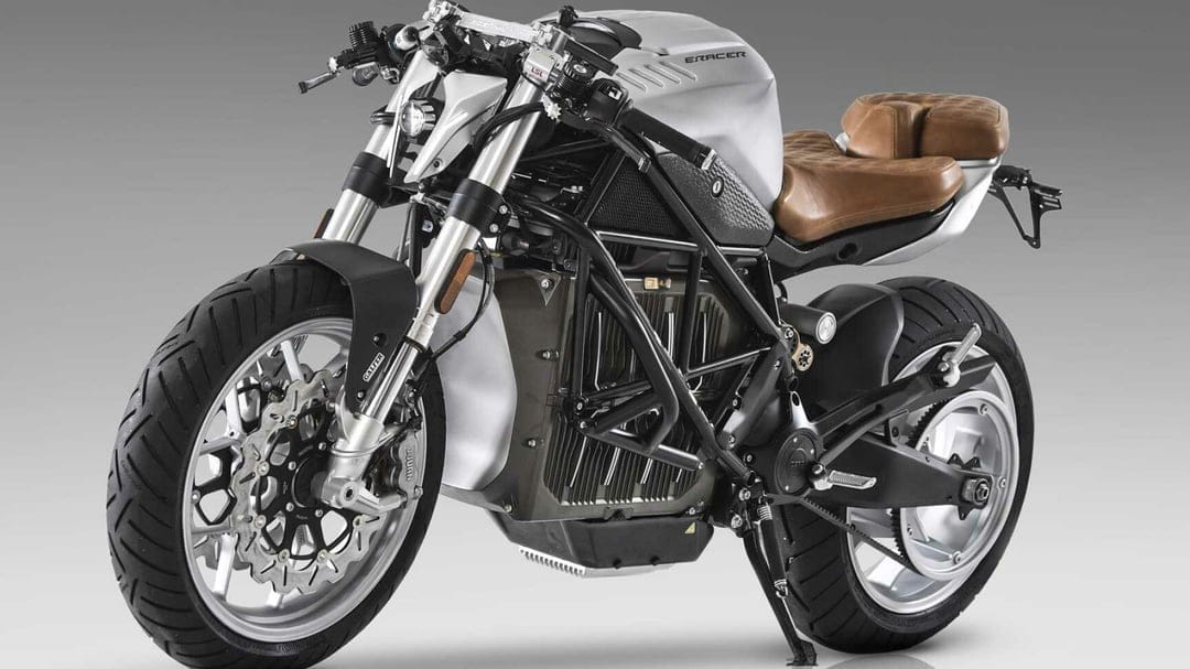 Profile of a custom silver electric motorcycle with brown leather seat and black trellis frame in a studio.