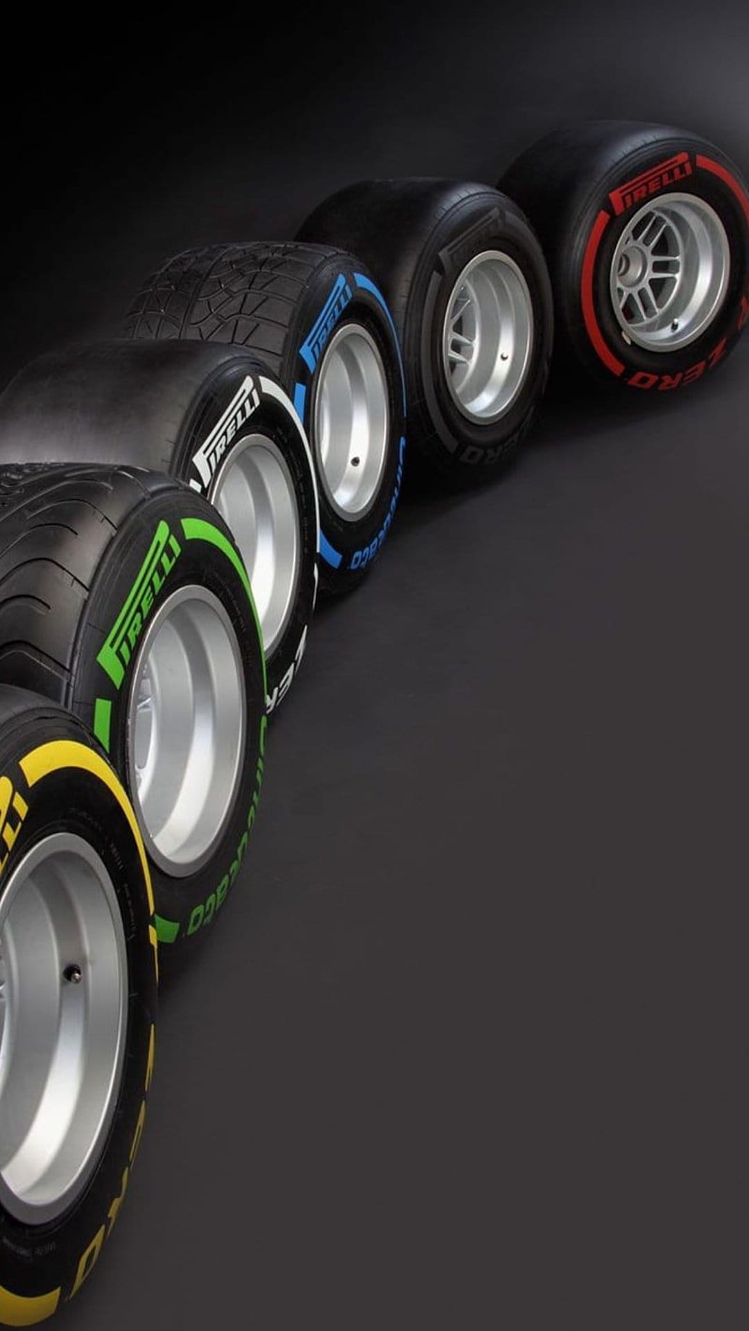 Pirelli Formula 1 tires with colorful sidewall markings are arranged in a row, showcasing rubber tread textures.