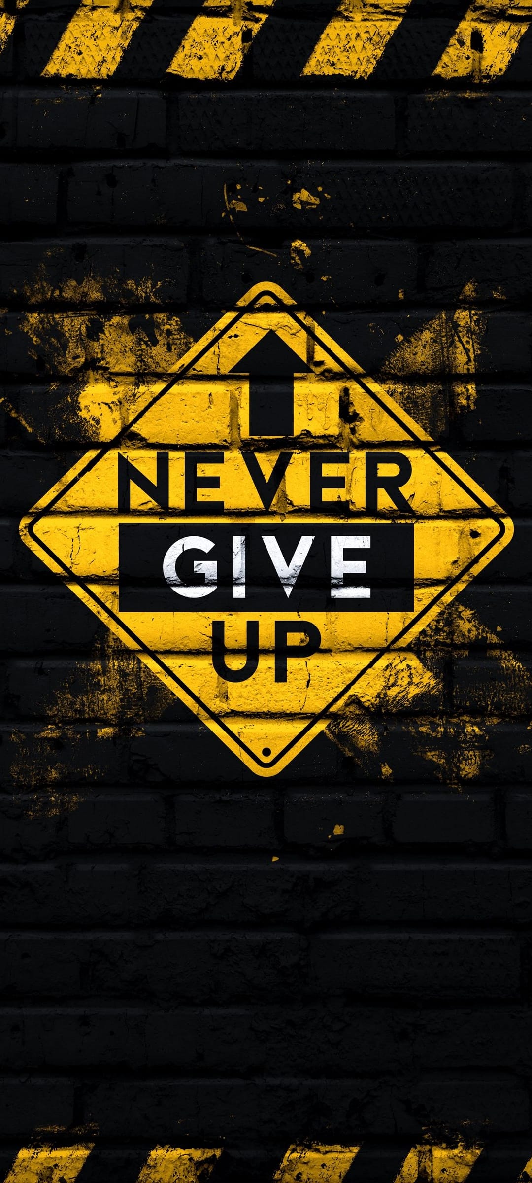 Never Give Up yellow warning sign mounted on a dark textured brick wall with high-contrast hazard stripes.