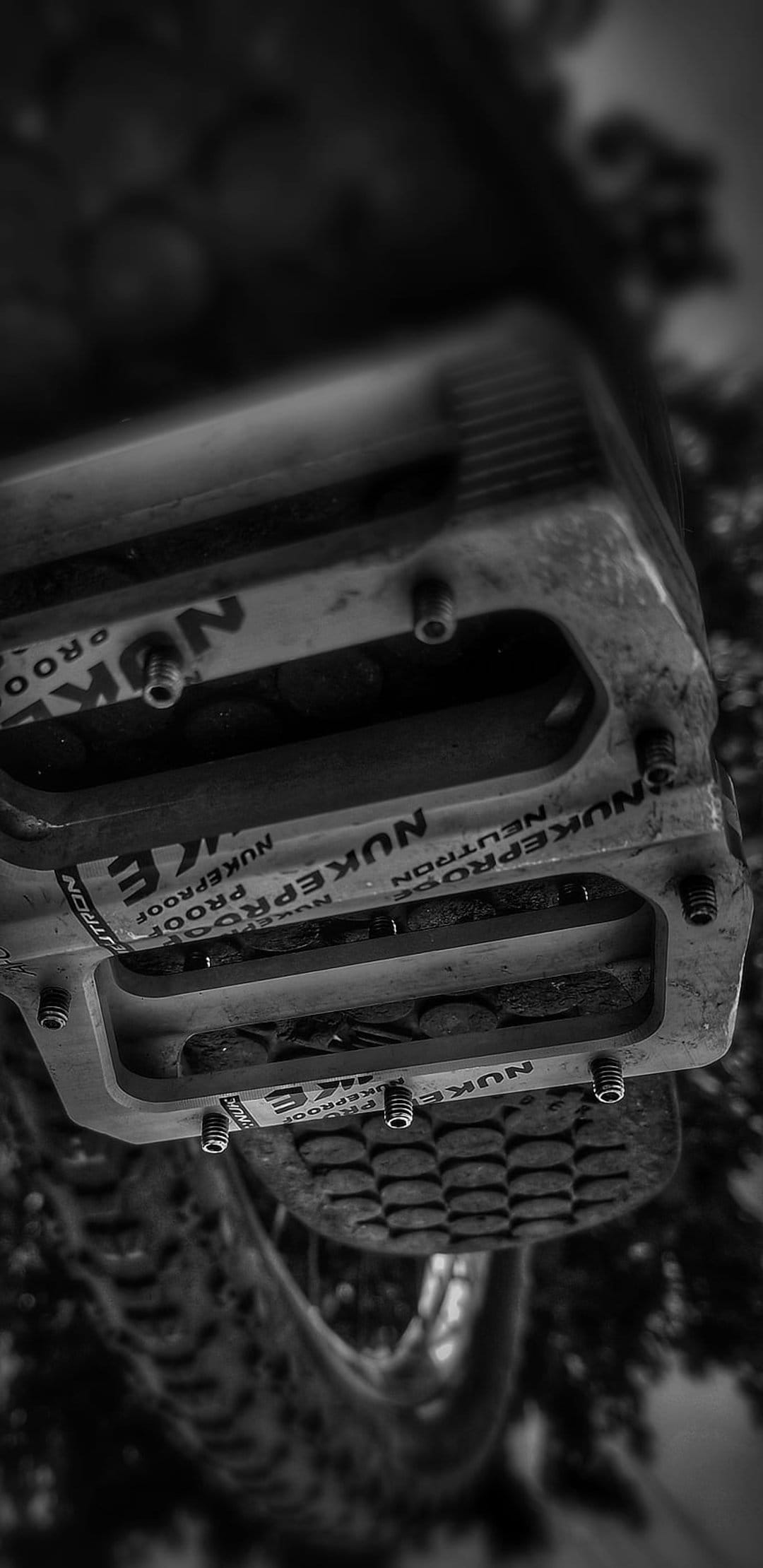 Nukeproof Neutron mountain bike pedals with metal pins shown in a high-contrast black and white macro view.
