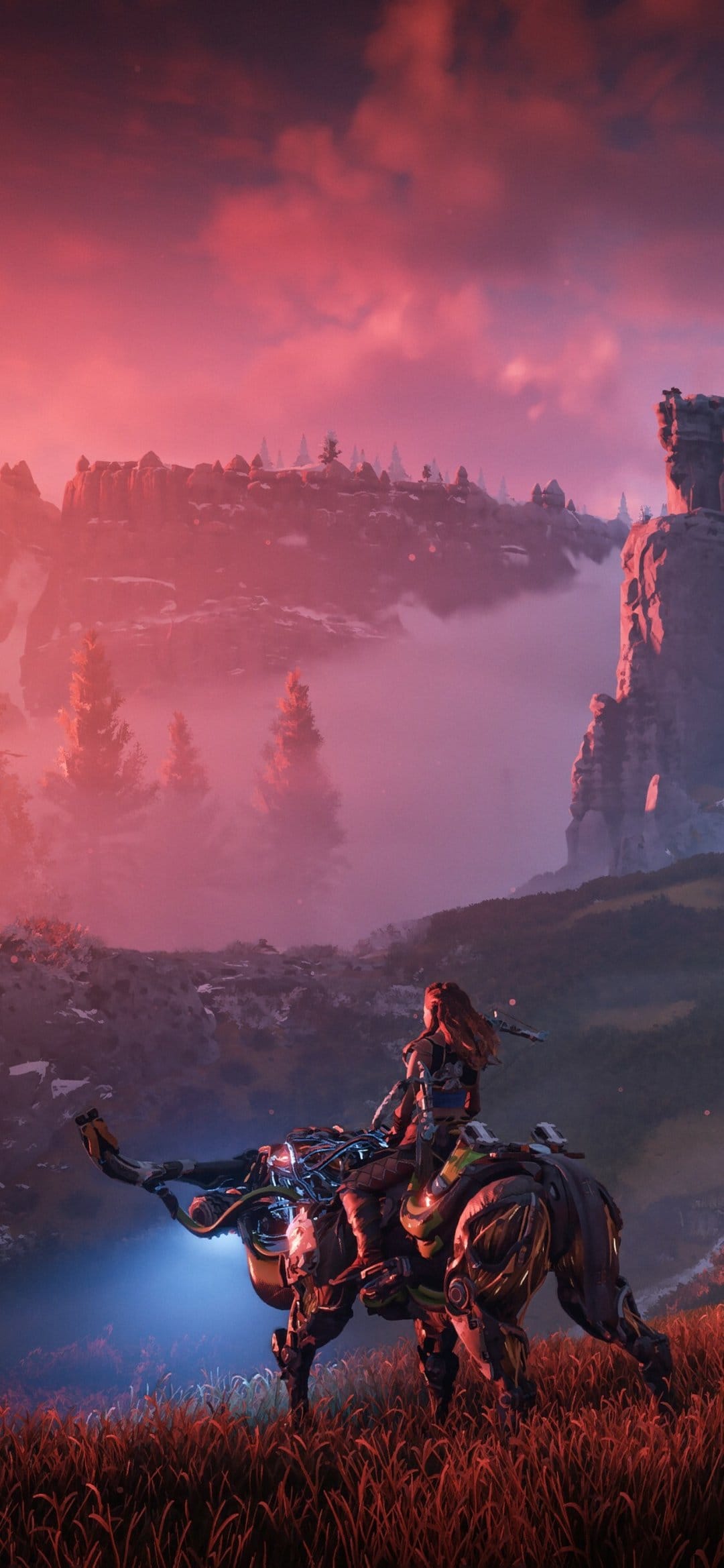 Aloy rides a glowing robotic beast through red-tinted mist and mountains under a vibrant sunset sky.