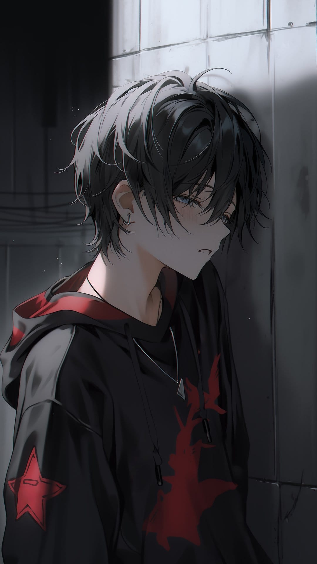 Young man with messy black hair wearing a black hoodie with a red star emblem against a textured urban wall.