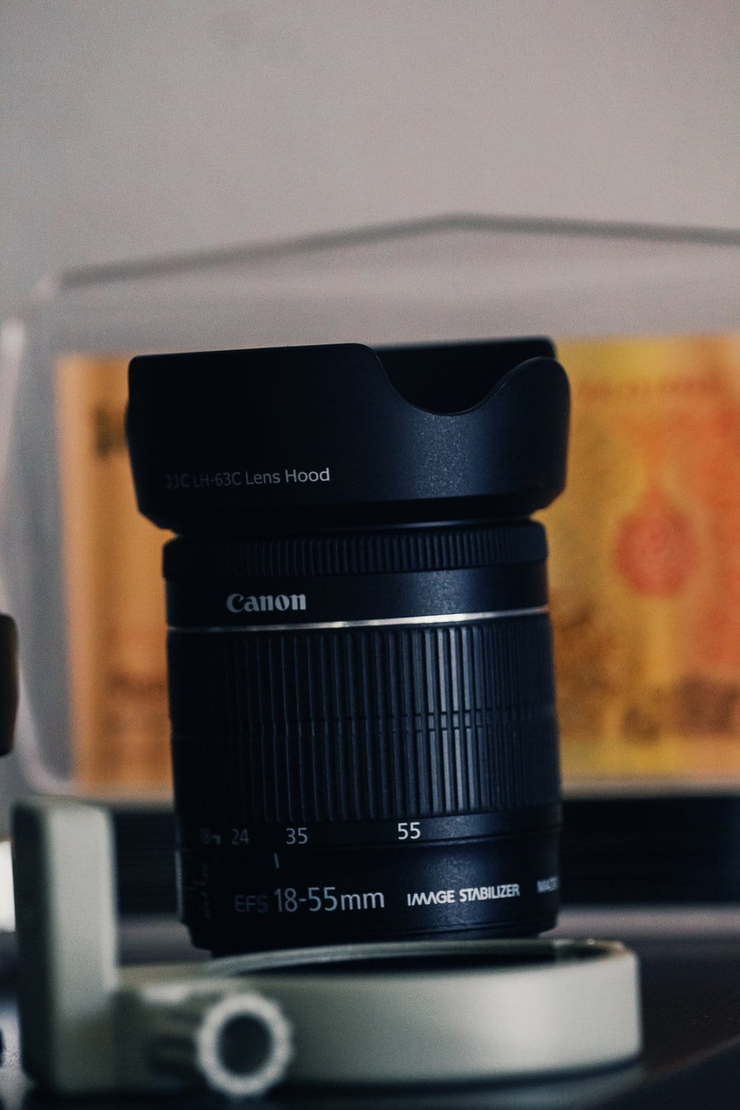 Canon 18-55mm EF-S lens with an attached hood features sharp focal markings and a white camera mount base.