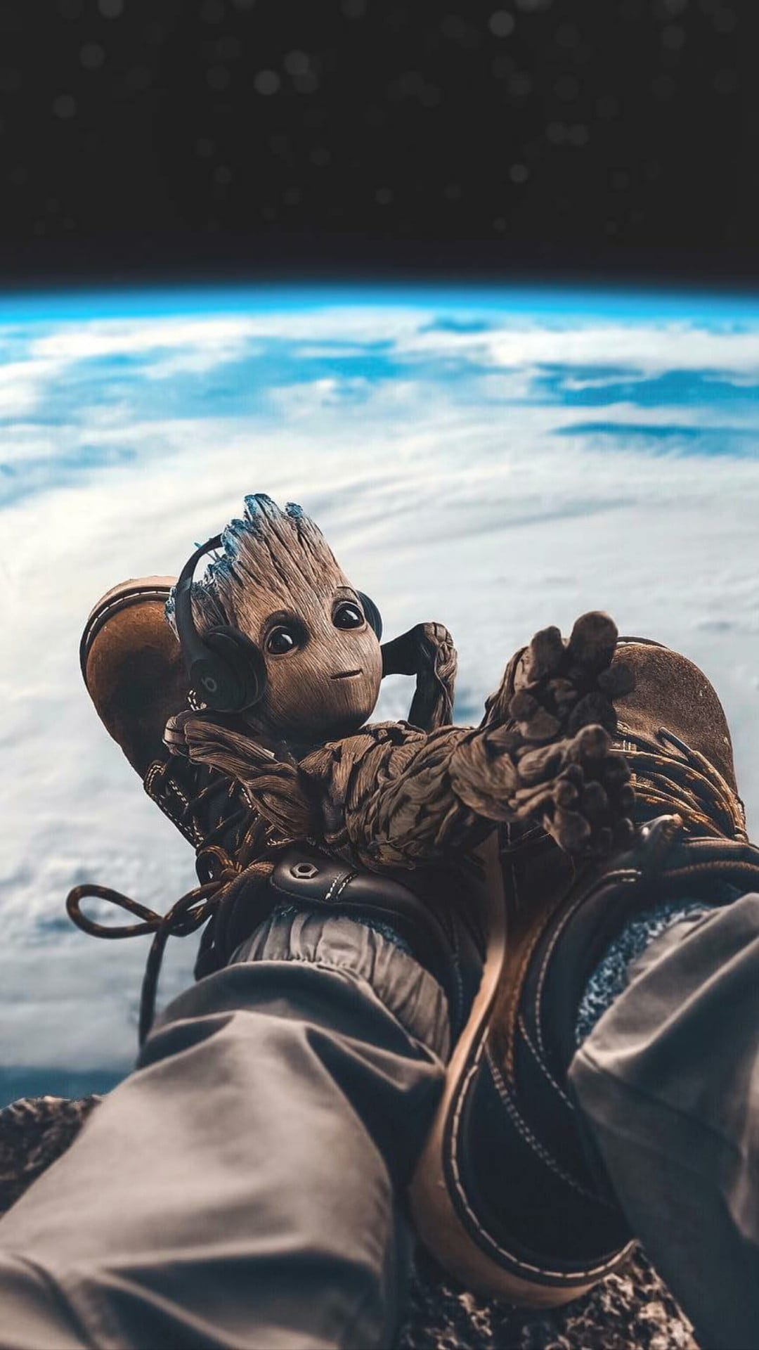 Baby Groot wearing a white spacesuit and headphones relaxes against a backdrop of Earth's blue horizon and stars.