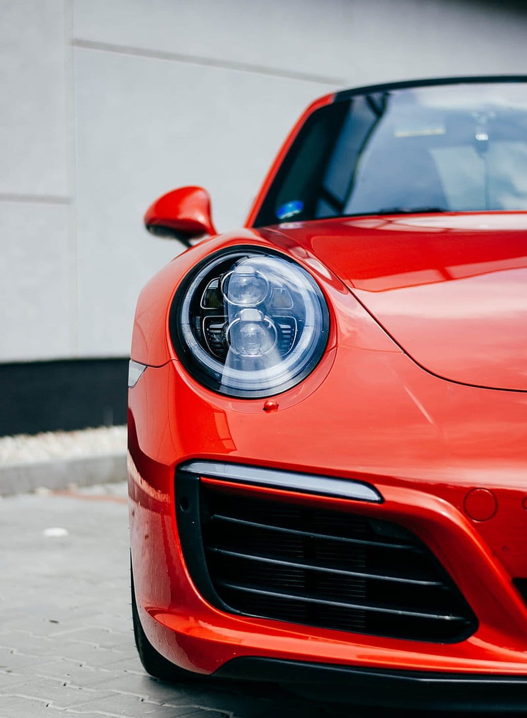 Porsche 911 front headlight and grille with glossy red paint, showcasing detailed LED matrix components and curves.