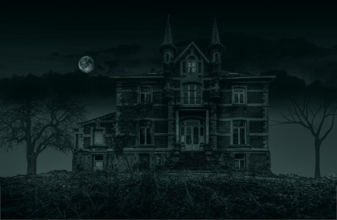 Crumbling gothic mansion silhouetted against a bright full moon with twisted bare trees and a misty night sky.