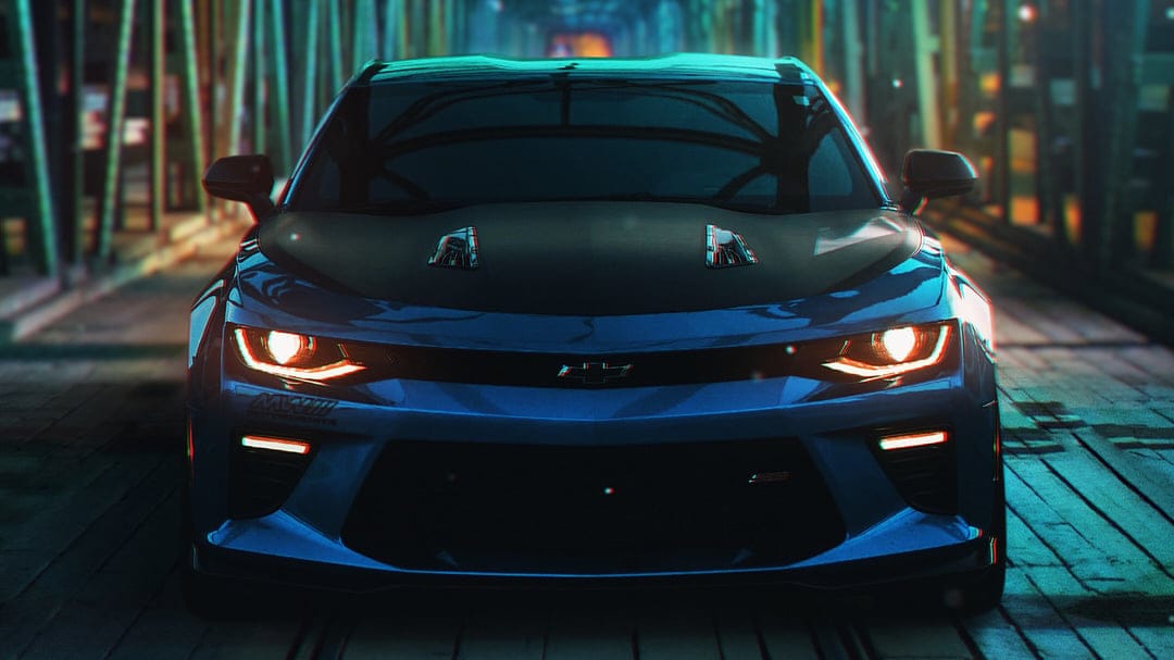 Blue Chevrolet Camaro SS with glowing orange headlights parked on a wooden bridge at night in teal lighting.