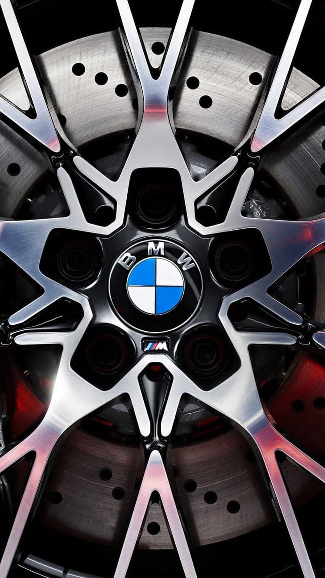 BMW M alloy wheel with polished spokes, carbon fiber trim, and a drilled brake rotor on a performance vehicle.