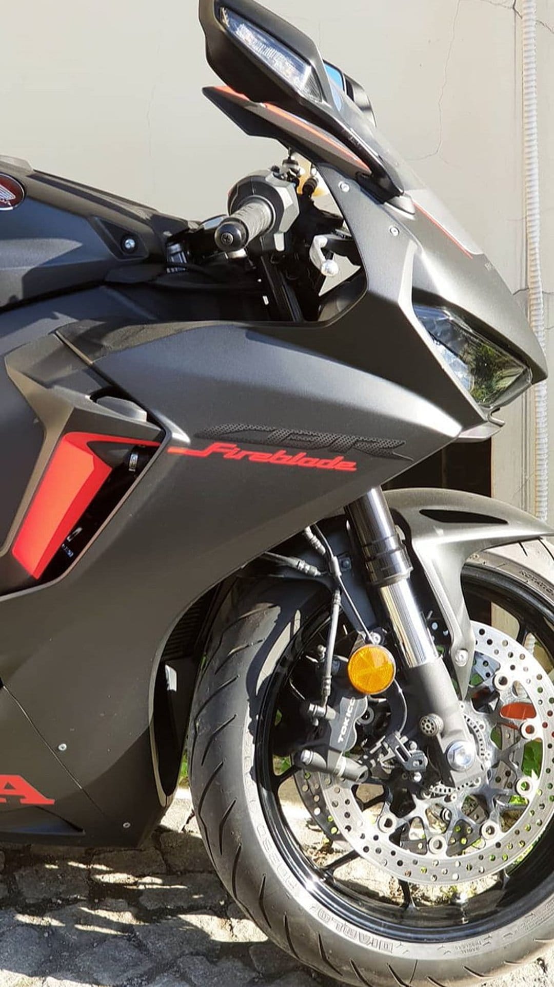 Honda CBR Fireblade front fairing with sharp headlights, red graphics, and a drilled disc brake on a black sportbike.