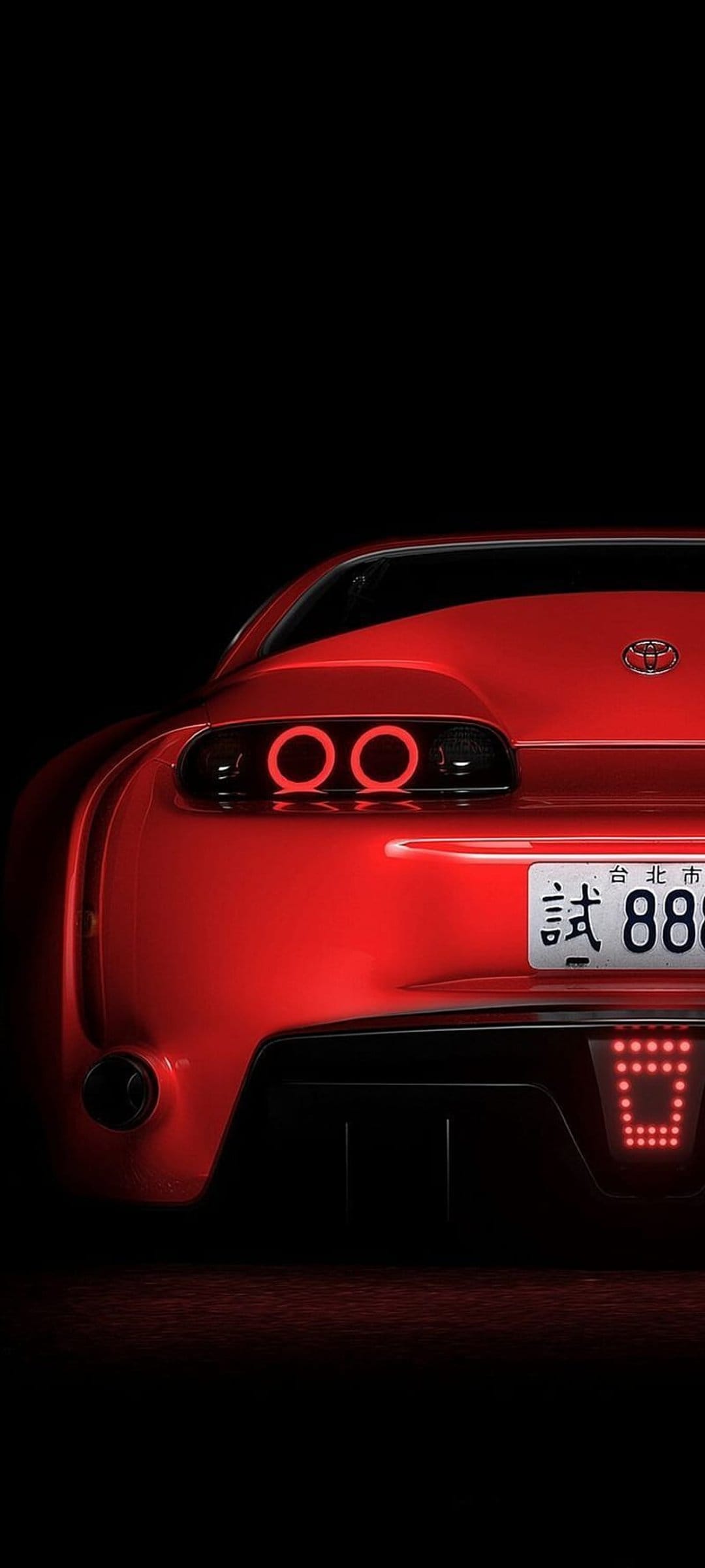 Toyota Supra rear view featuring illuminated red circular taillights and a license plate against a dark background.
